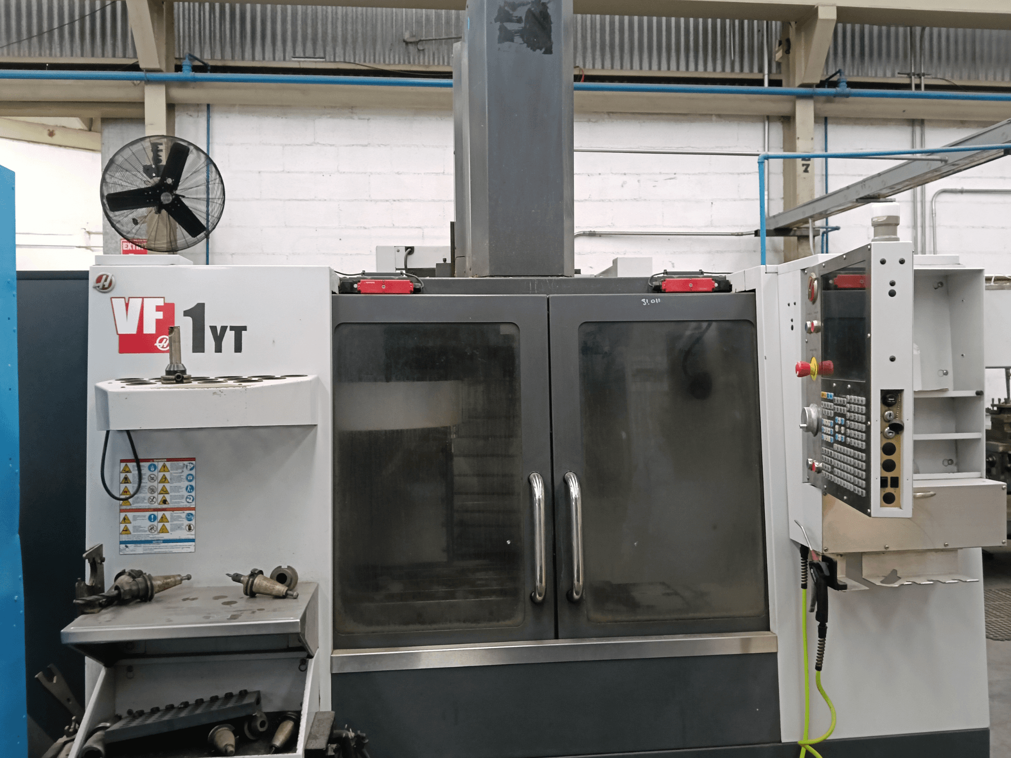 Vista frontal del centro de mecanizado vertical HAAS VF-1YT-1 con el panel de control y las herramientas situadas en el lateral.