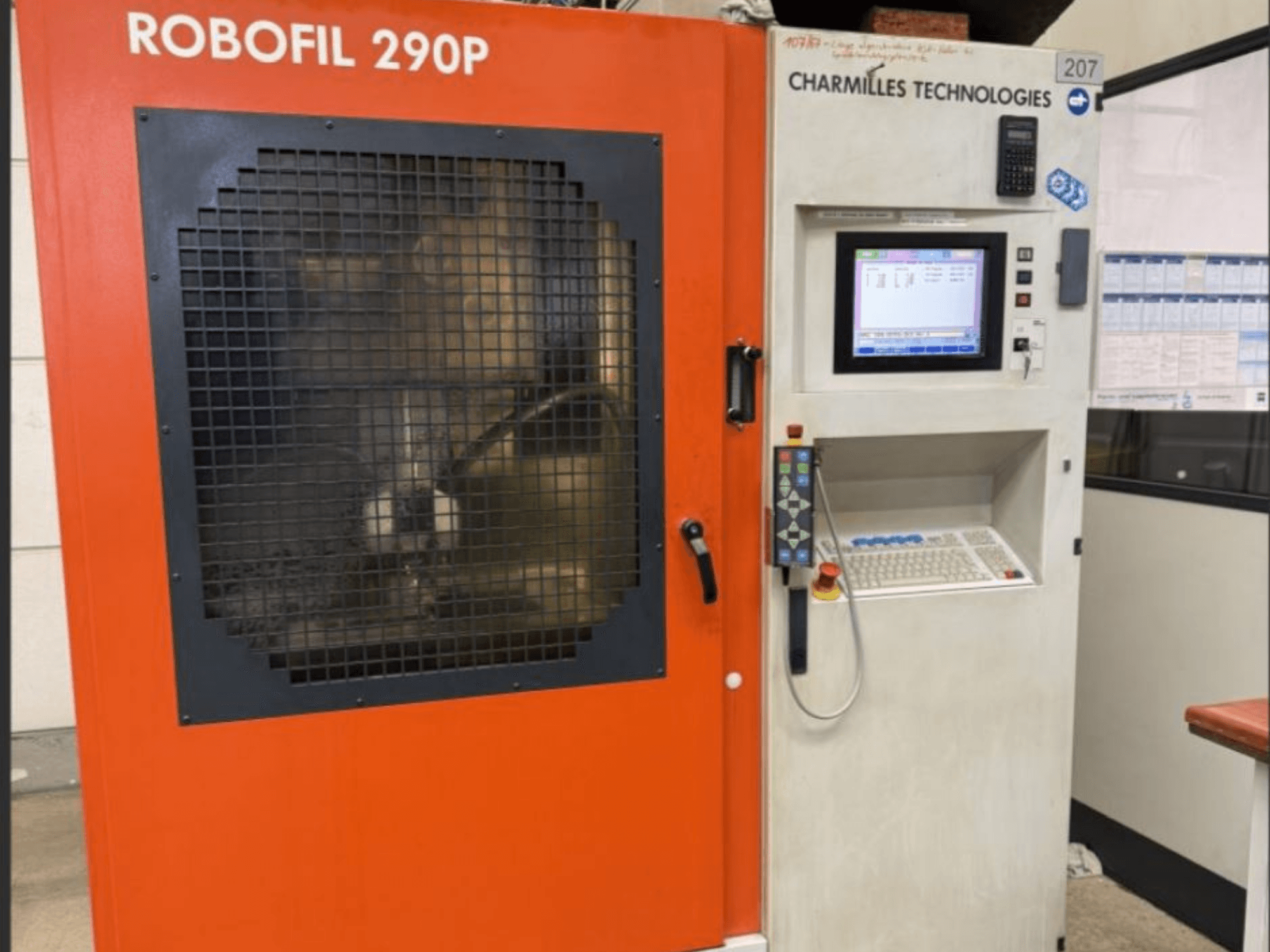 Vista frontal de la máquina de electroerosión por hilo Robofil 290P de CHARMILLES TECHNOLOGIES con panel de control y zona de trabajo protegida por rejilla.