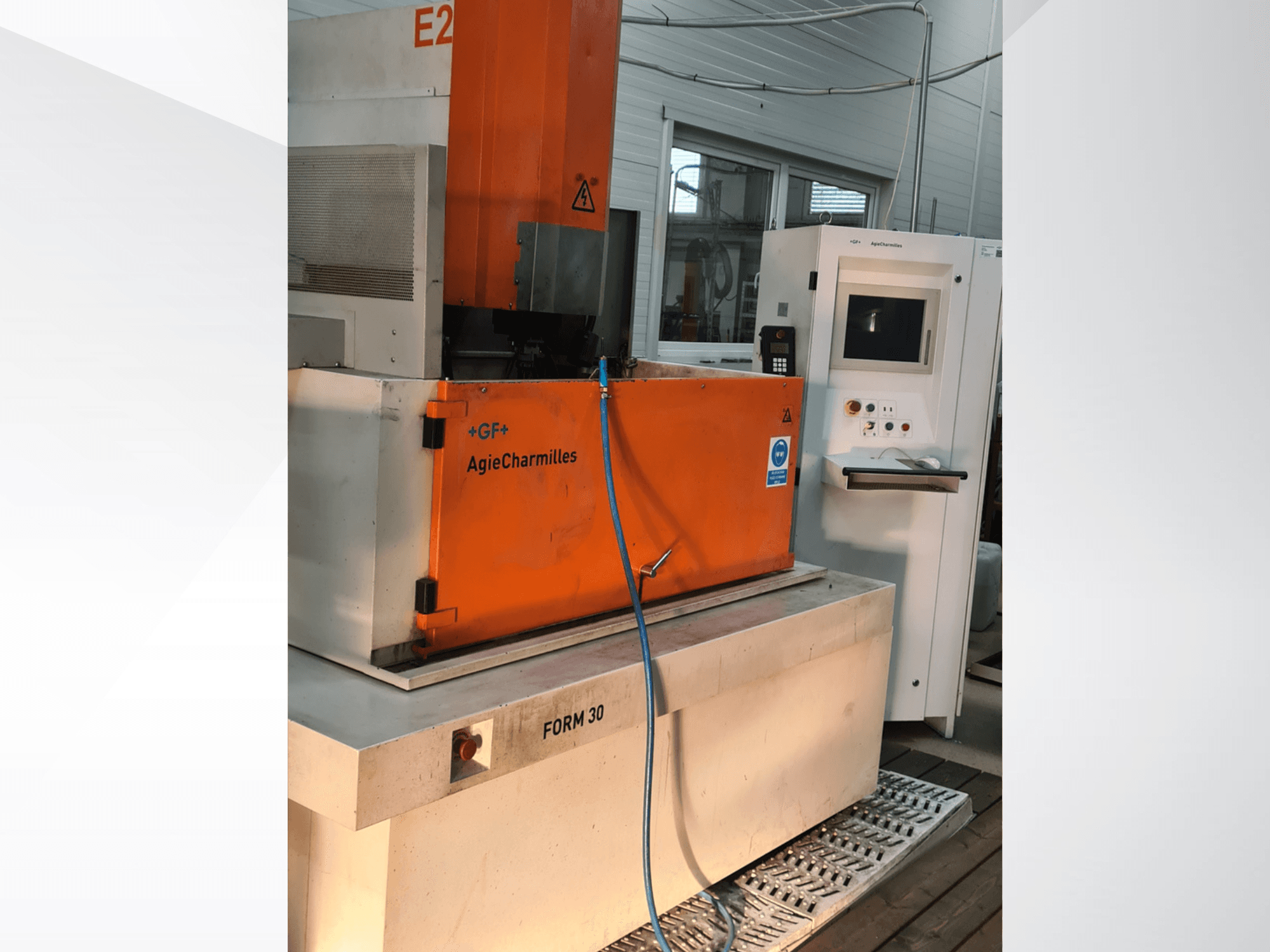 Máquina de electroerosión por penetración AgieCharmilles FORM 30, vista frontal, en la que se aprecian el armario de control naranja y la manguera de agua.