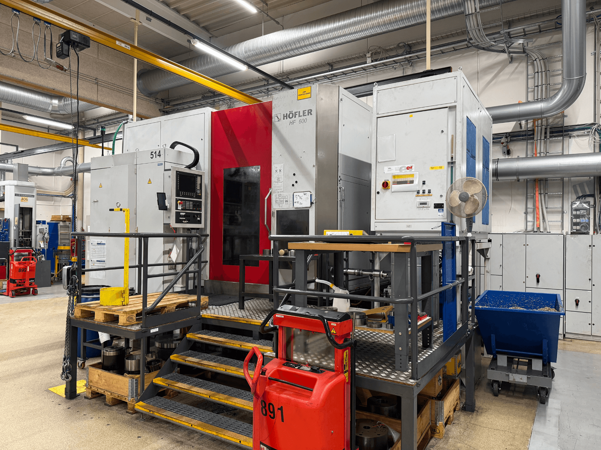 Máquina herramienta HOFLER HF 600, vista lateral, mostrando el panel de control, la barrera de seguridad amarilla y el entorno del taller.