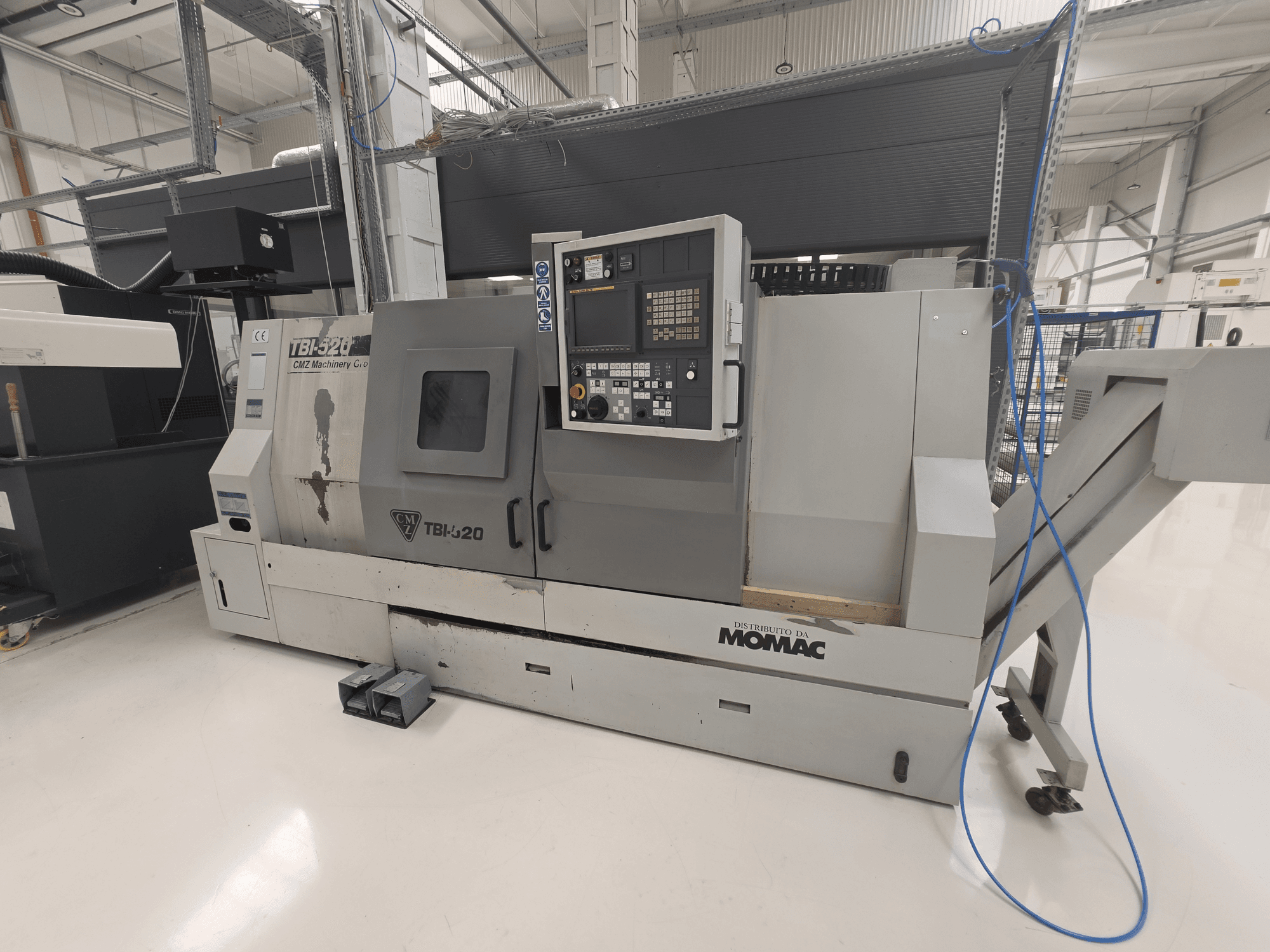 Torno horizontal CMZ TBI-520, vista lateral, en la que se aprecian el panel de control y los detalles de la maquinaria en un entorno industrial limpio.