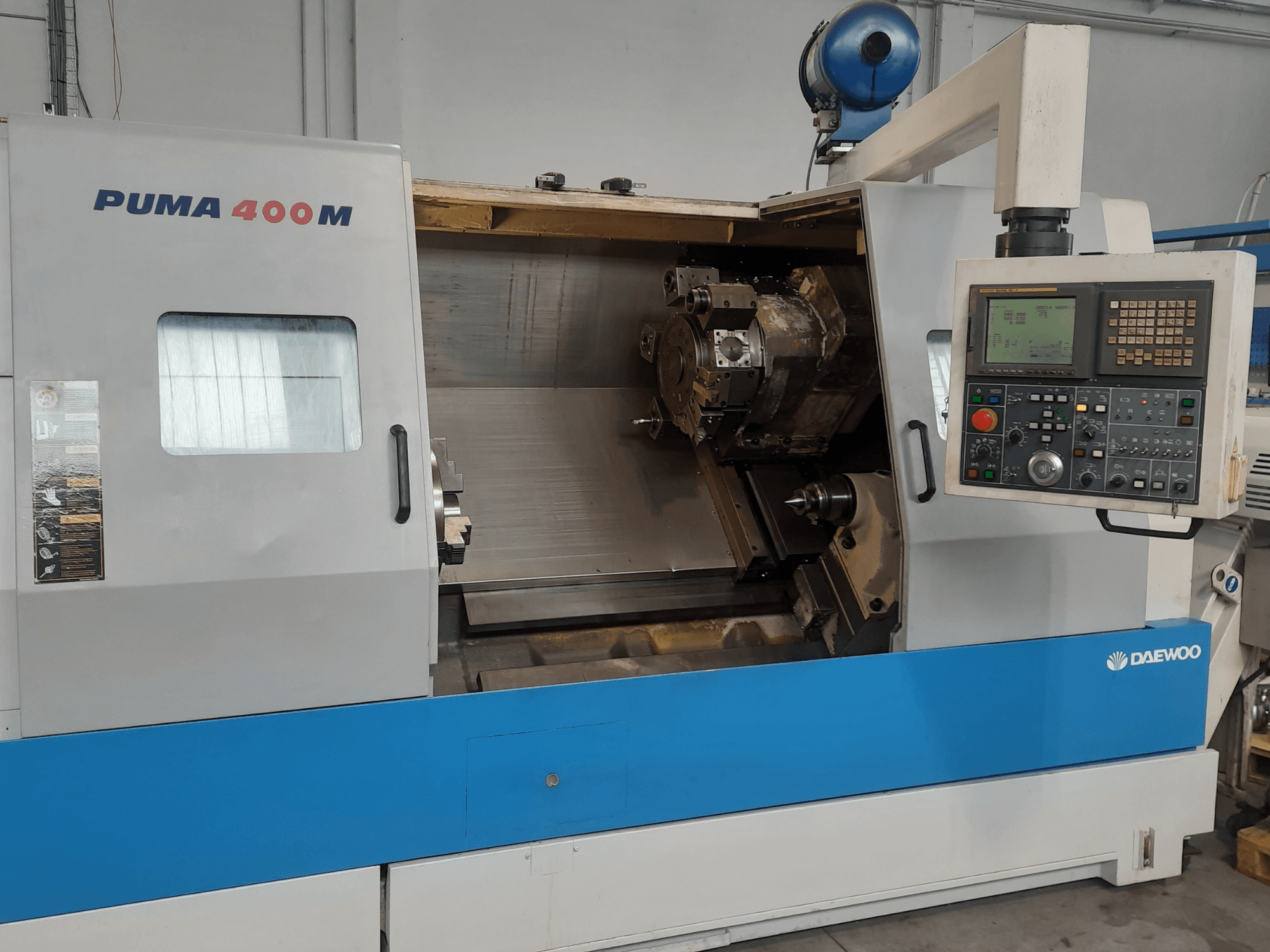 Vista frontal de un torno horizontal DAEWOO PUMA 400MB, en la que se aprecian los mandos y la herramienta de corte en la cámara.