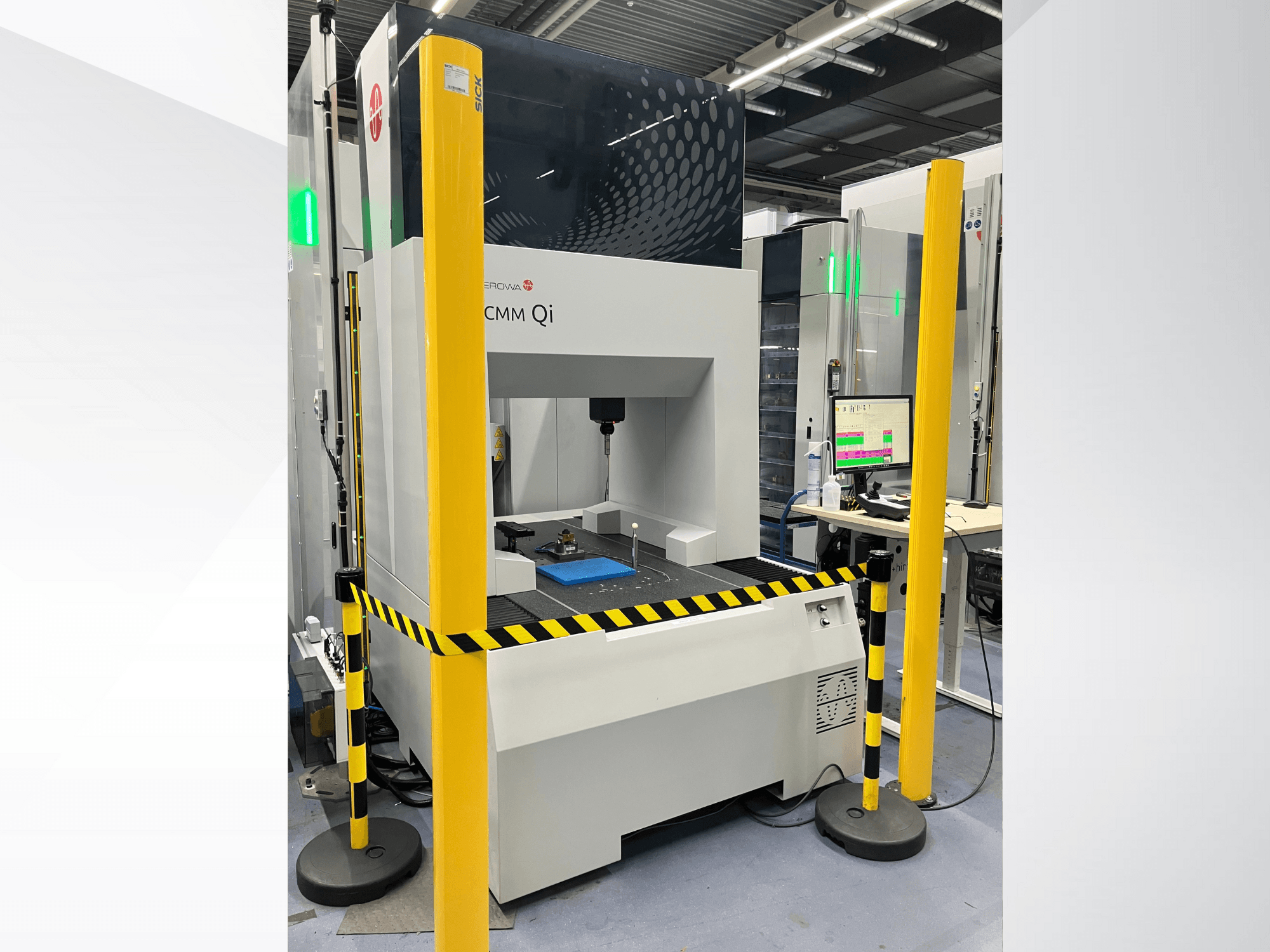Máquina de medición de coordenadas MMC Qi de Aerovent, vista frontal con barreras de seguridad y monitor que muestra los datos de medición.