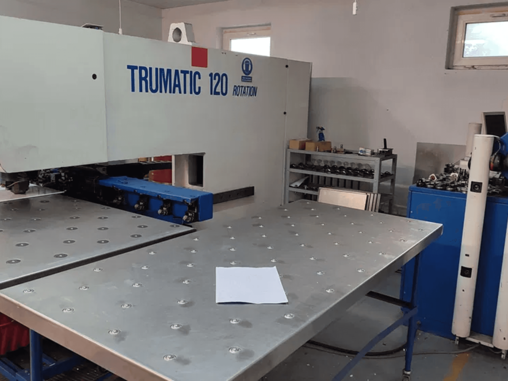 Punzonadora CNC TRUMPF TRUMATIC 120R vista de frente, con una mesa metálica con agujeros punzonados y una chapa en blanco.