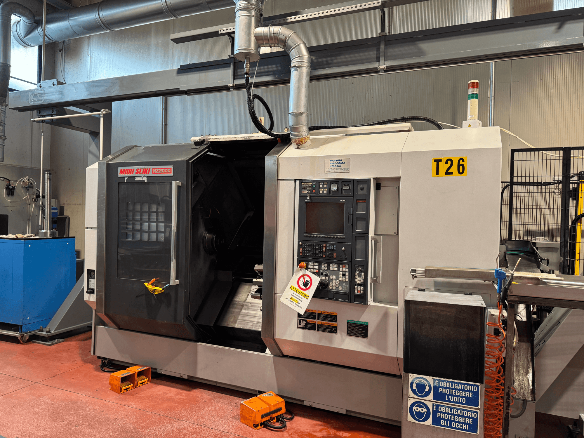 Centro de torneado y fresado MORI SEIKI NZ-2000/T2/Y2, vista frontal, con panel de control, señalización de seguridad y configuración industrial.