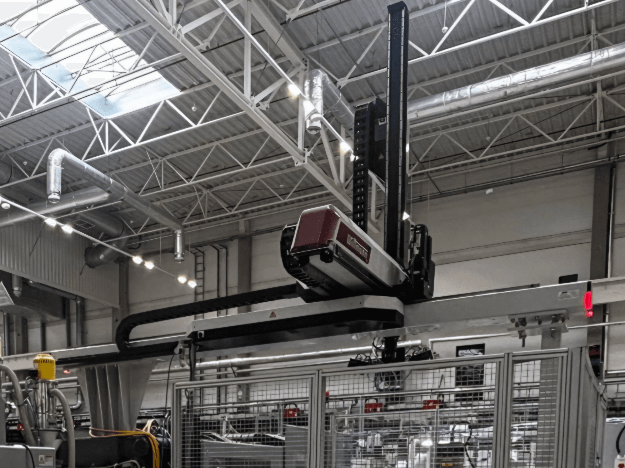 Máquina de procesamiento de plástico WITTMANN W832PRO en un entorno industrial, vista lateral en la que se aprecia el sistema suspendido y el fondo industrial.