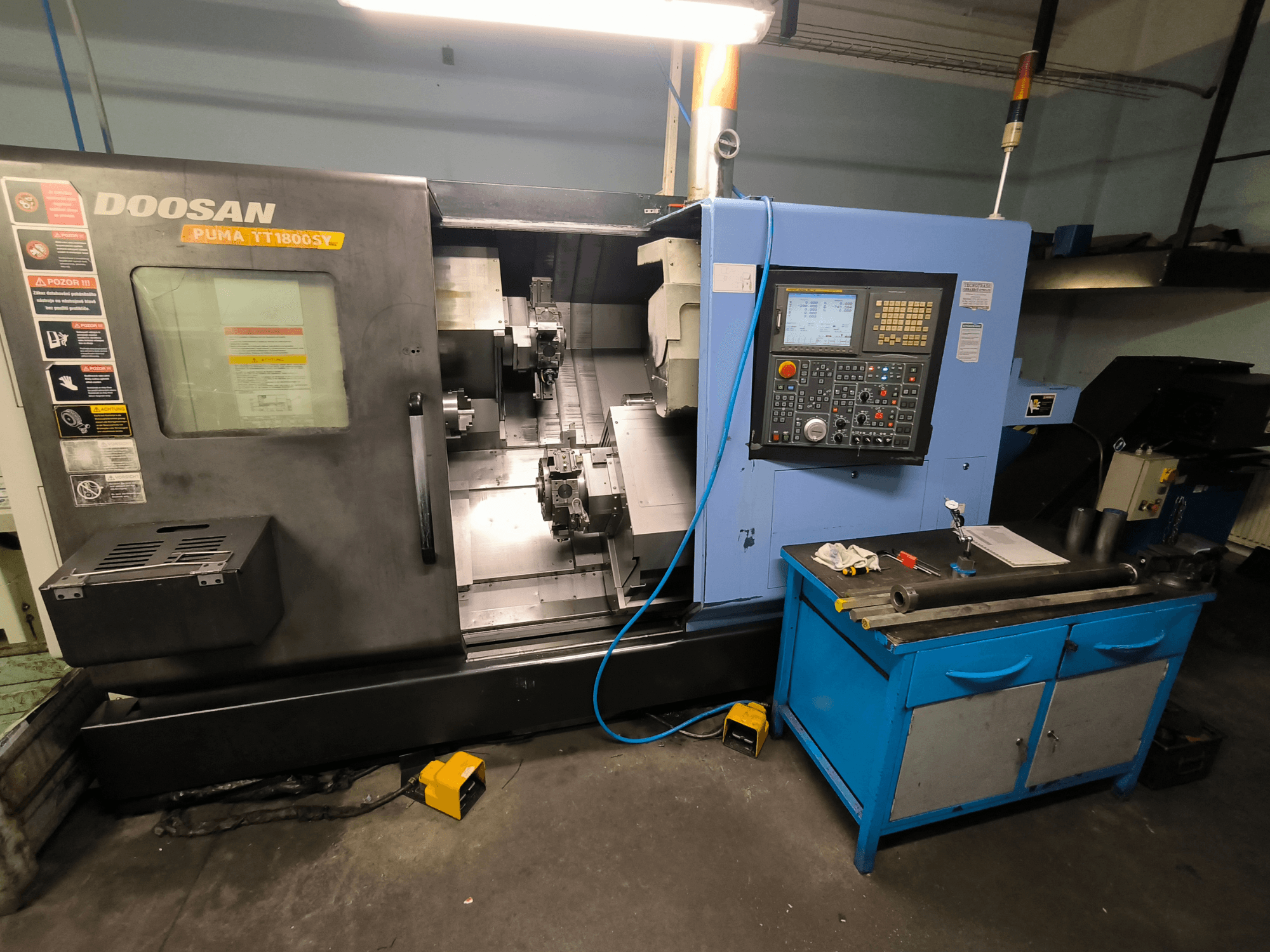 Torno CNC Doosan Puma TT1800SY, vista frontal, mostrando panel de control, área de trabajo con herramientas y componentes de la máquina.