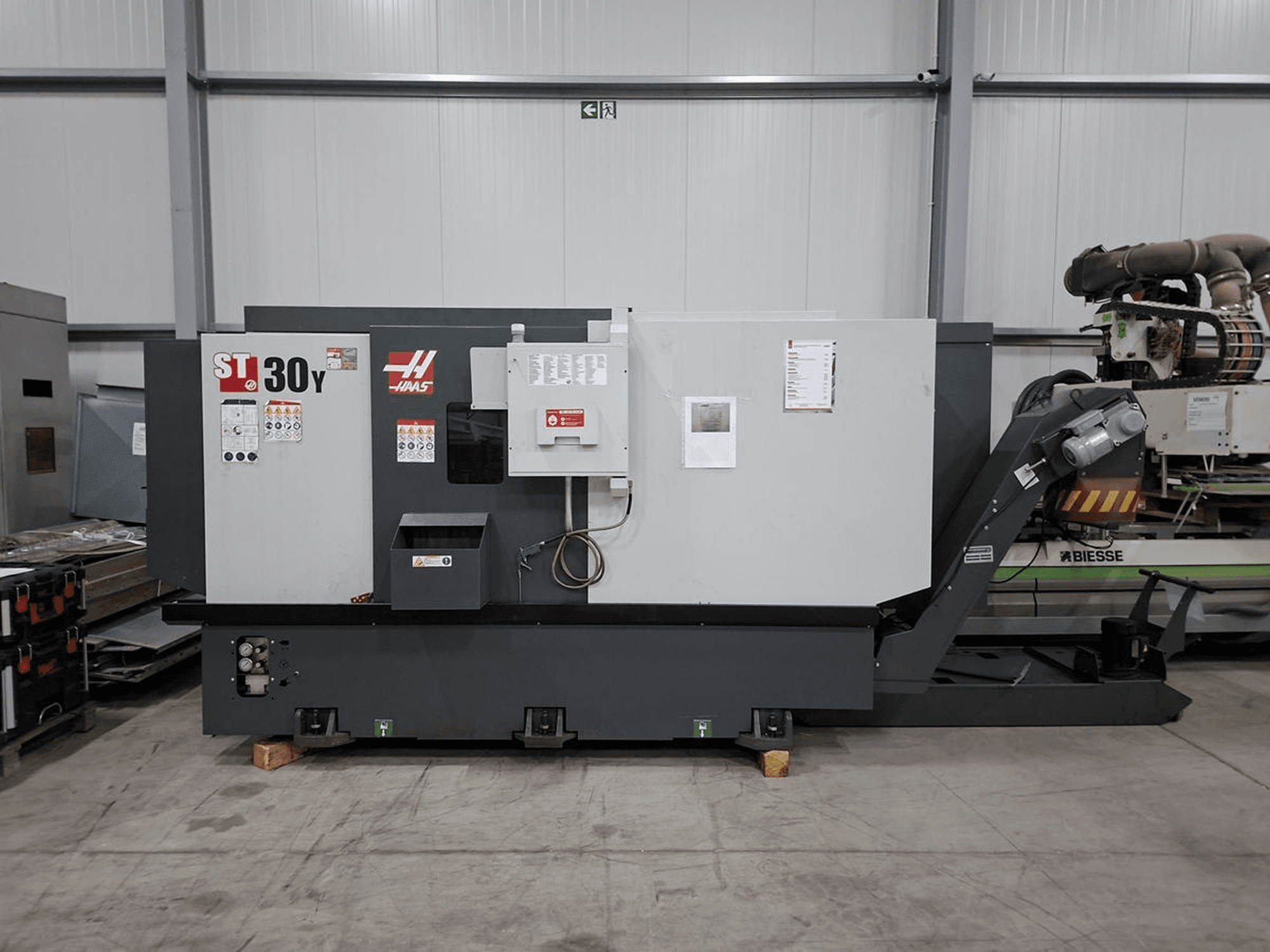Torno horizontal Haas ST-30Y visto de perfil, en el que se aprecian los mandos, las etiquetas y su sólida construcción en un amplio taller.
