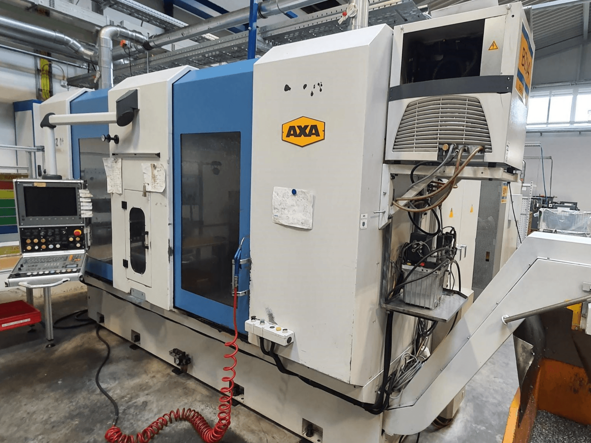 Centro de mecanizado vertical AXA DBZ, vista frontal, con panel de control y detalle visible del sistema de refrigeración.