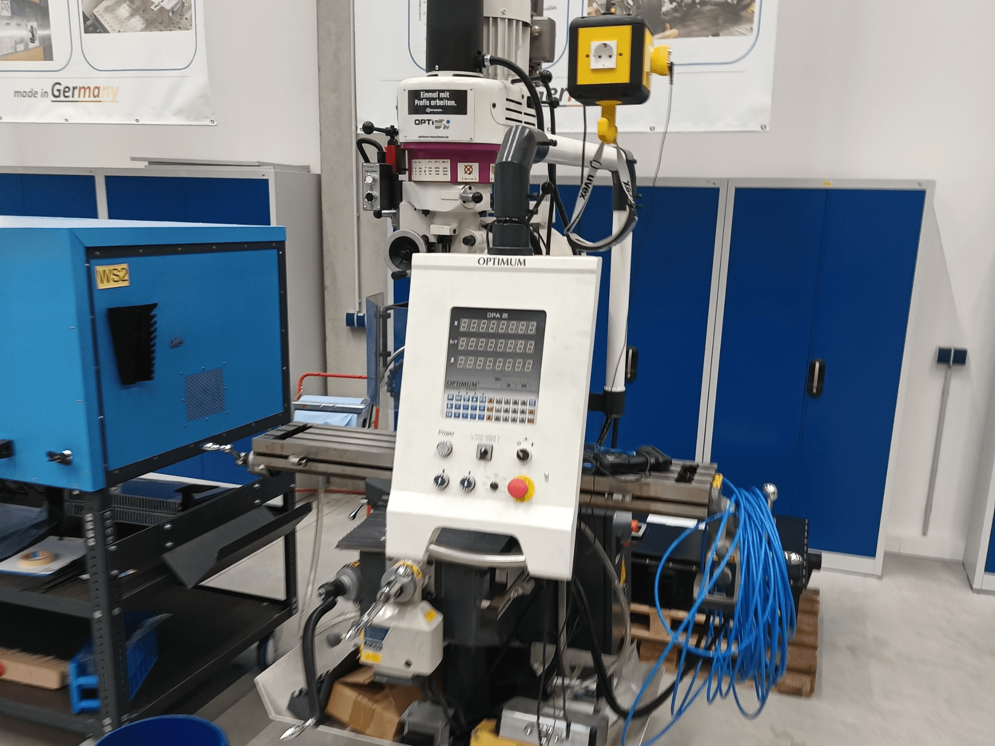 Centro de mecanizado vertical Optimum OPTImill MF 2V; vista frontal en la que se aprecian el panel de control, el husillo y el carro de apoyo azul.