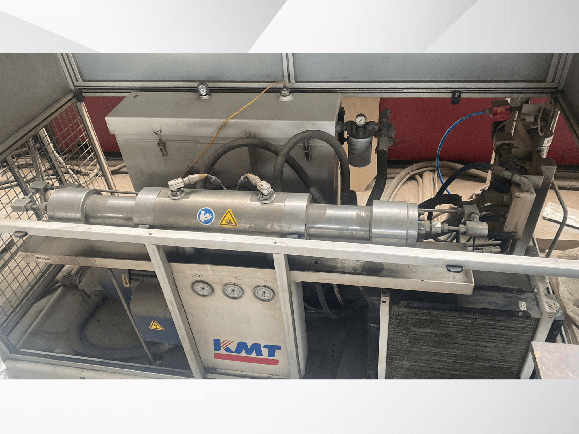 Máquina hidráulica KMT en vista frontal, con manómetros, mangueras y carcasa metálica, ideal para aplicaciones industriales.