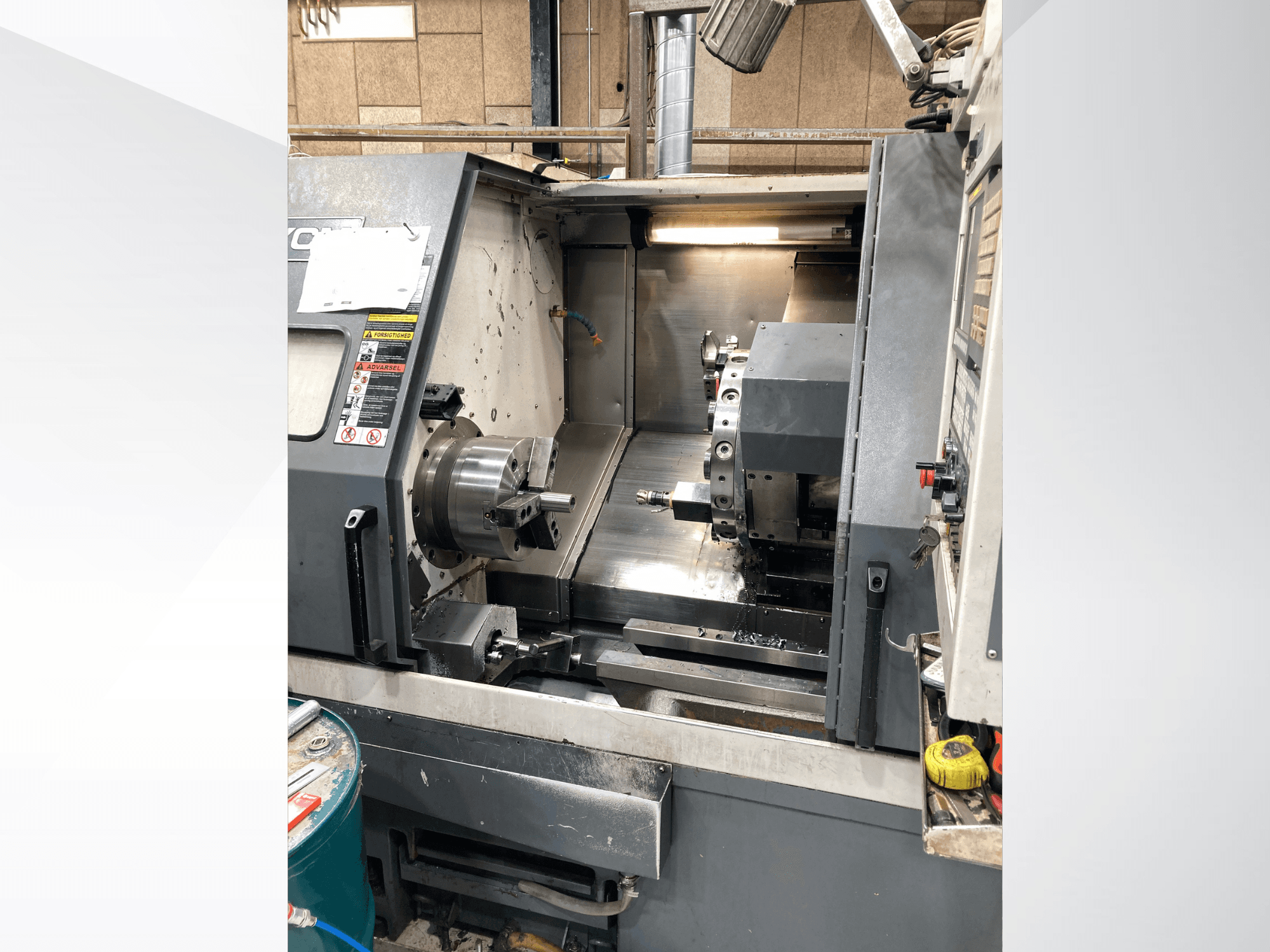 Máquina de torneado horizontal YCM GT-300LMB, vista frontal, mostrando el panel de control y el plato giratorio con la configuración de herramientas.