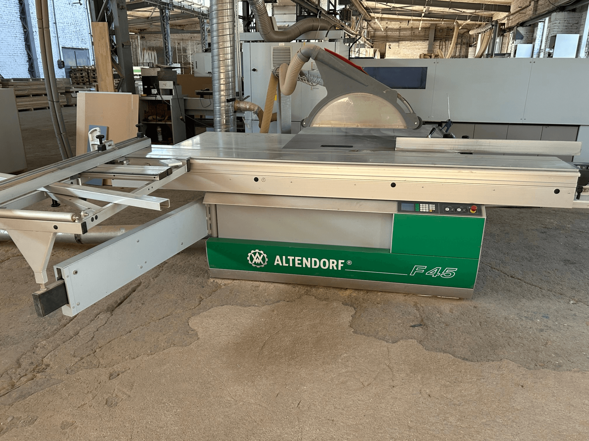 Sierra para paneles Altendorf F 45, vista frontal, en la que se aprecian la mesa de corte, la protección de la hoja y el panel de control de la máquina de color verde y gris.