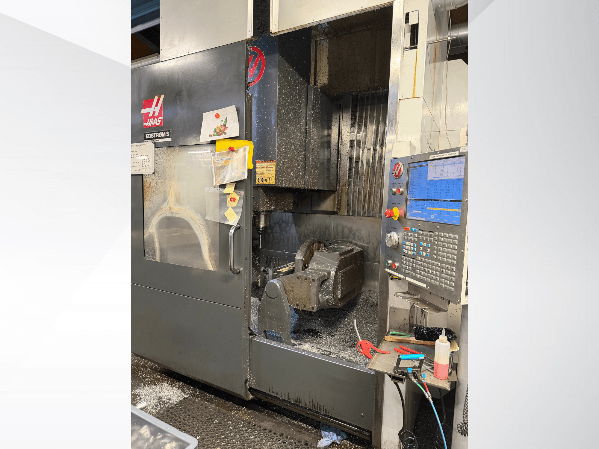 Máquina CNC Haas modelo EDSTROM S, vista frontal, mostrando pieza metálica, panel de control y virutas metálicas en el interior.