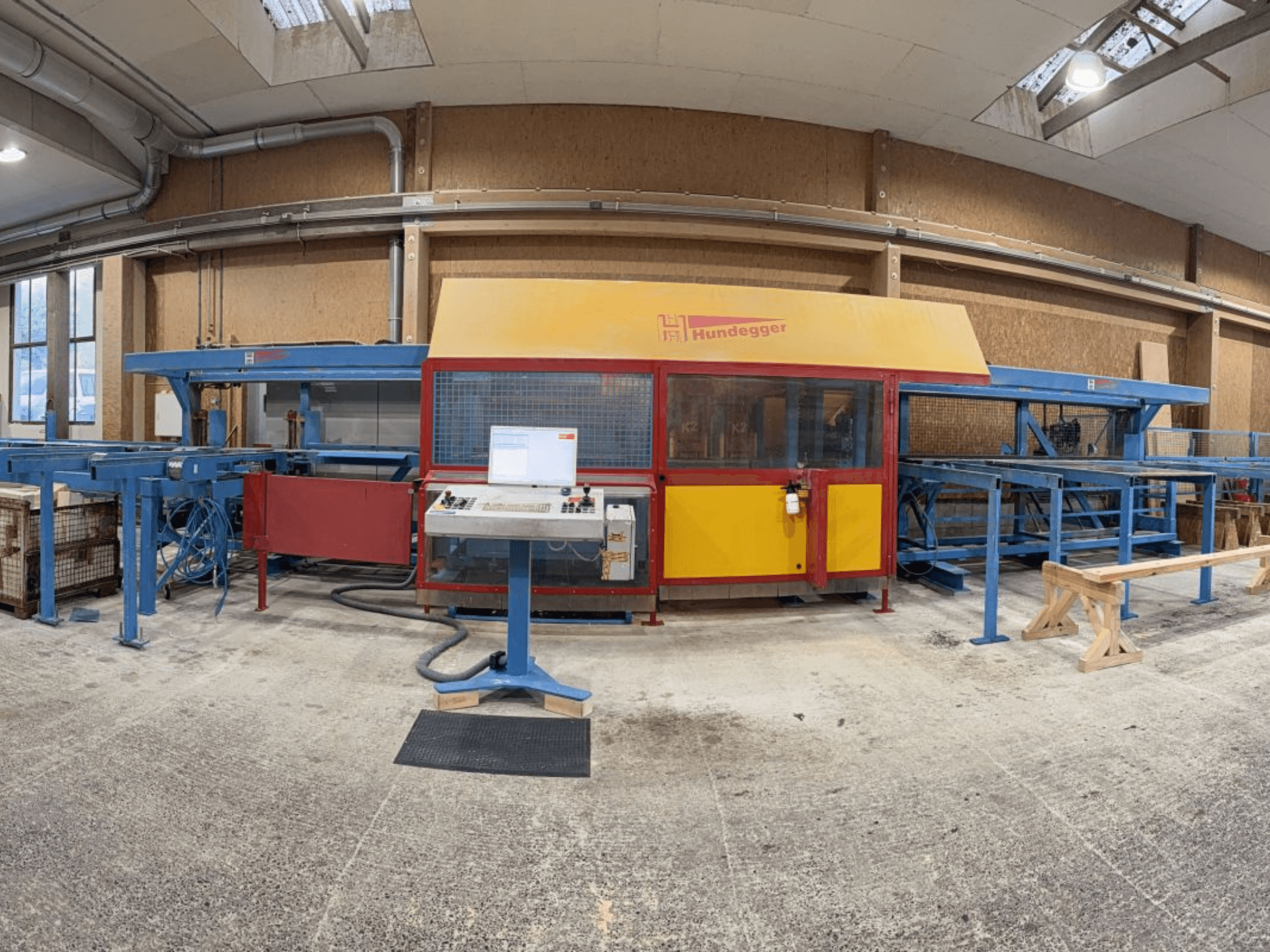 Vista frontal de la línea completa de producción de madera HUNDEGGER K2-4-450, con panel de control y sistema de transporte.