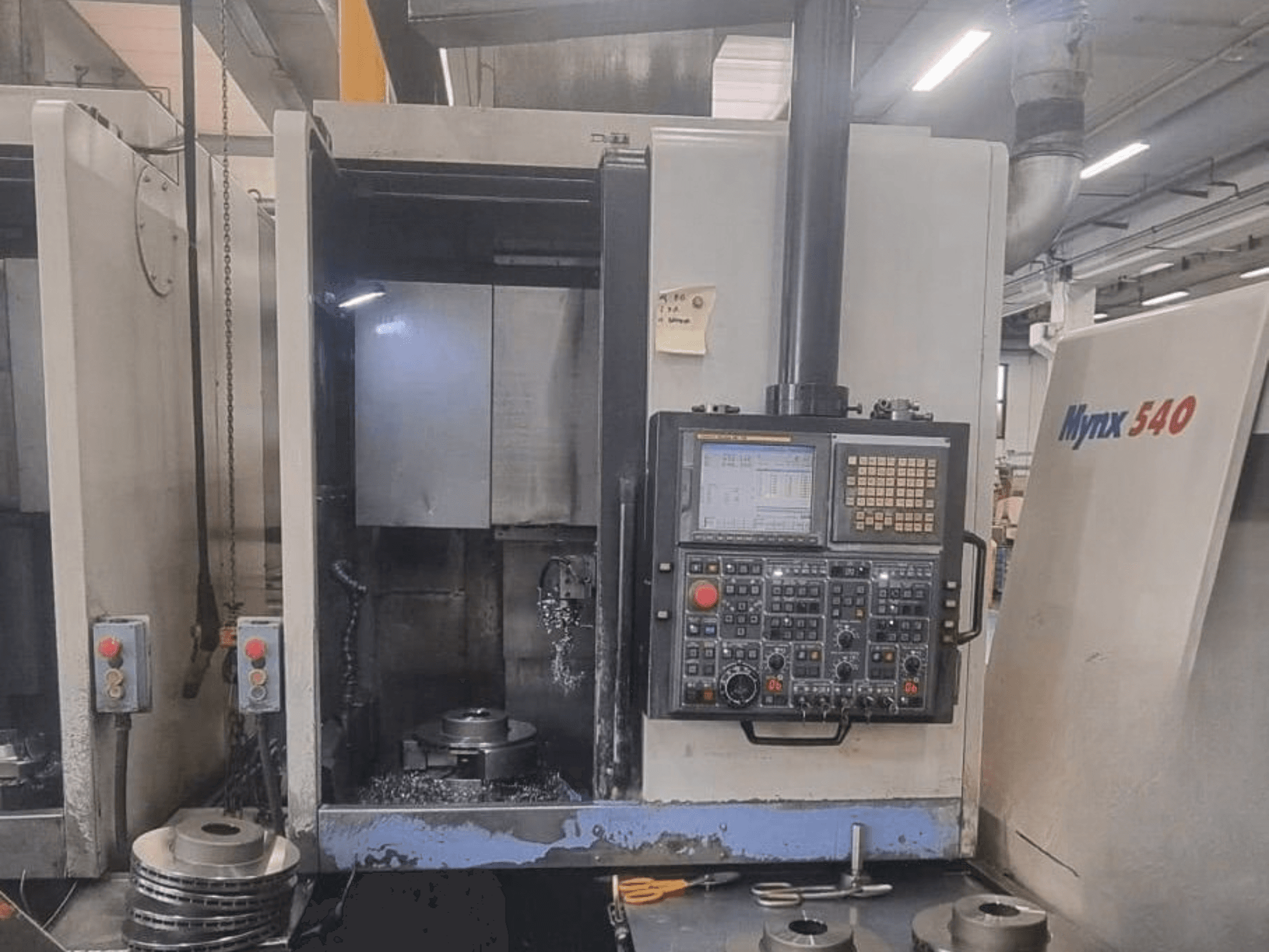 Vista frontal de un torno vertical DOOSAN PUMA V400-2SP, en la que se aprecian el panel de control y la colocación de la pieza de trabajo en el interior de la máquina.