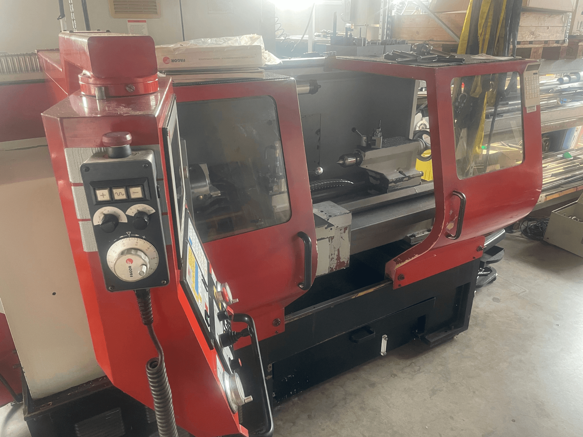 Torno horizontal EMCO EMCOMAT 200X1000, vista lateral, en la que se aprecian los mandos, la cabina acristalada y la configuración del torno.