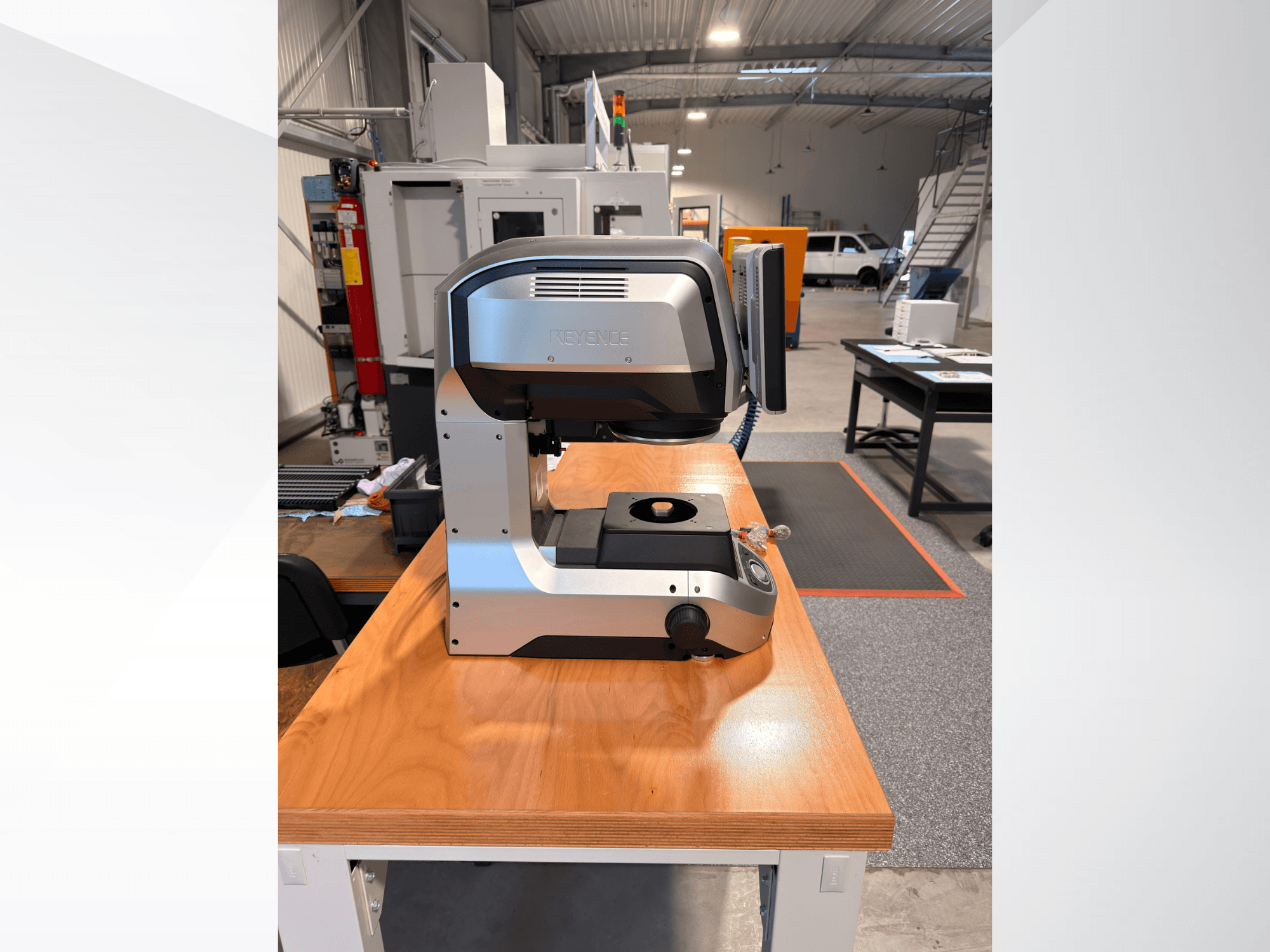 Vista frontal de la máquina de medición óptica IM-8005 de KEYENCE sobre una mesa de madera, en la que se aprecian su elegante diseño y su interfaz de funcionamiento.