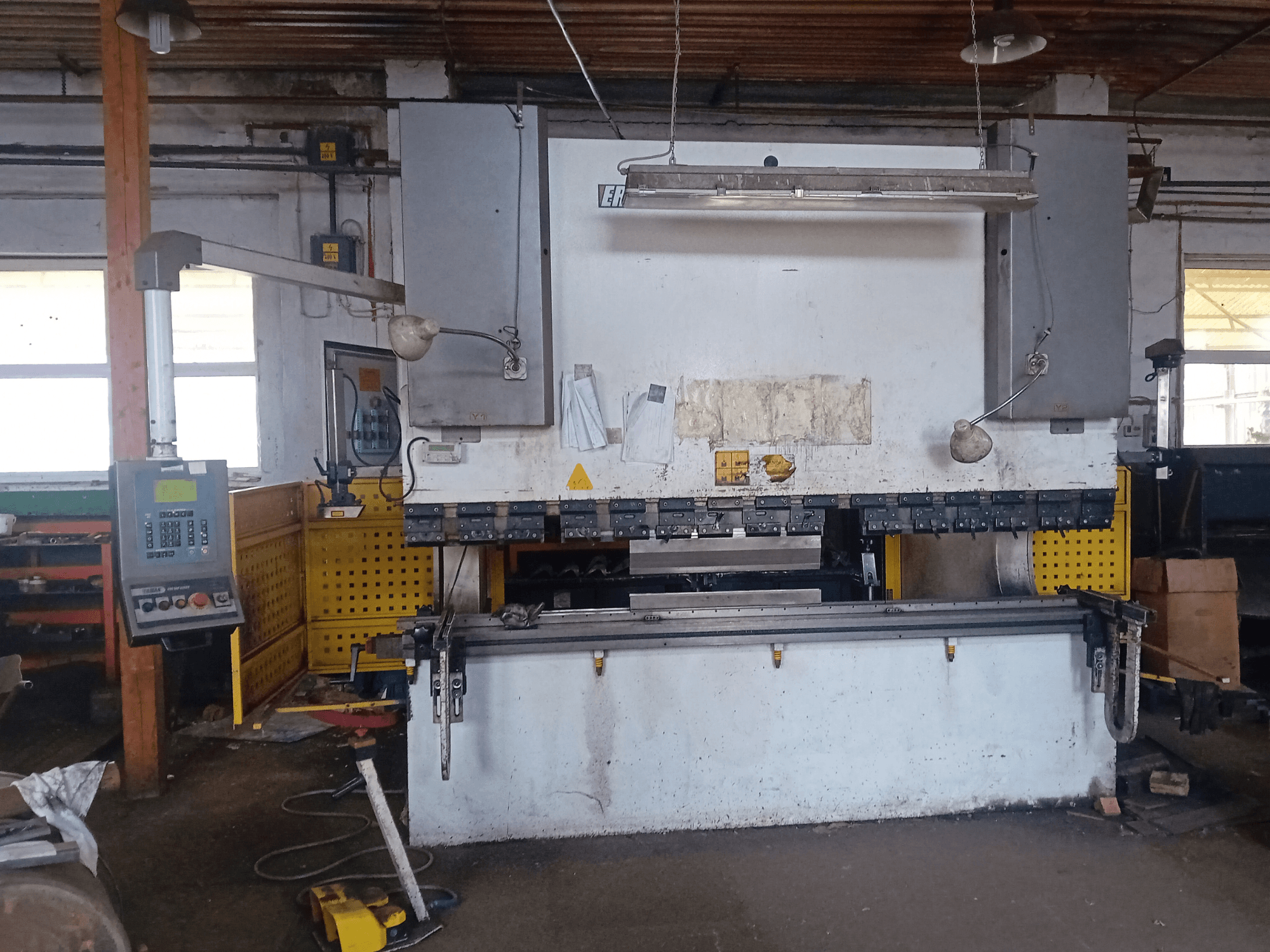 Prensa hidráulica CNC HAP 3100x300 de ERMAK en vista frontal, con panel de control y banco de trabajo en un taller.