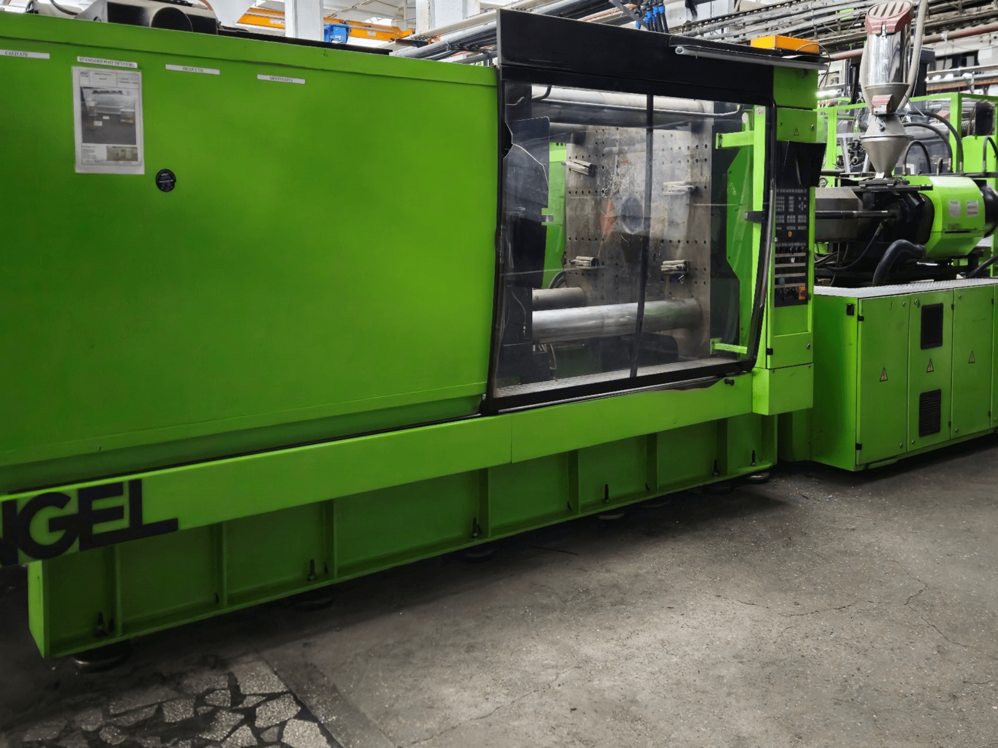 Máquina de moldeo por inyección Engel verde, vista lateral, con panel de control y gran ventana de visualización.