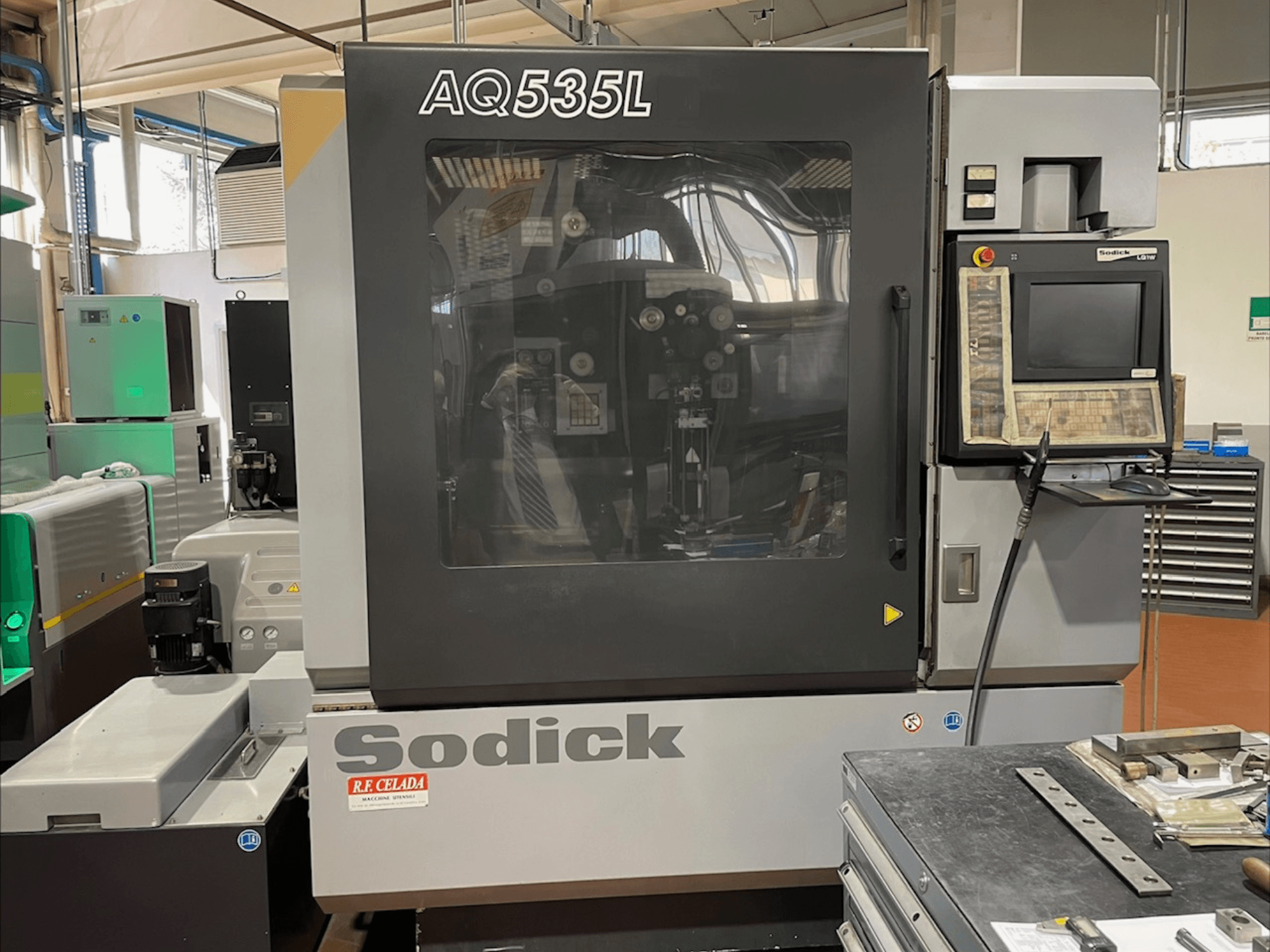 Vista frontal de la máquina de electroerosión por hilo Sodick AQ535L, con panel de control y cubierta protectora transparente.
