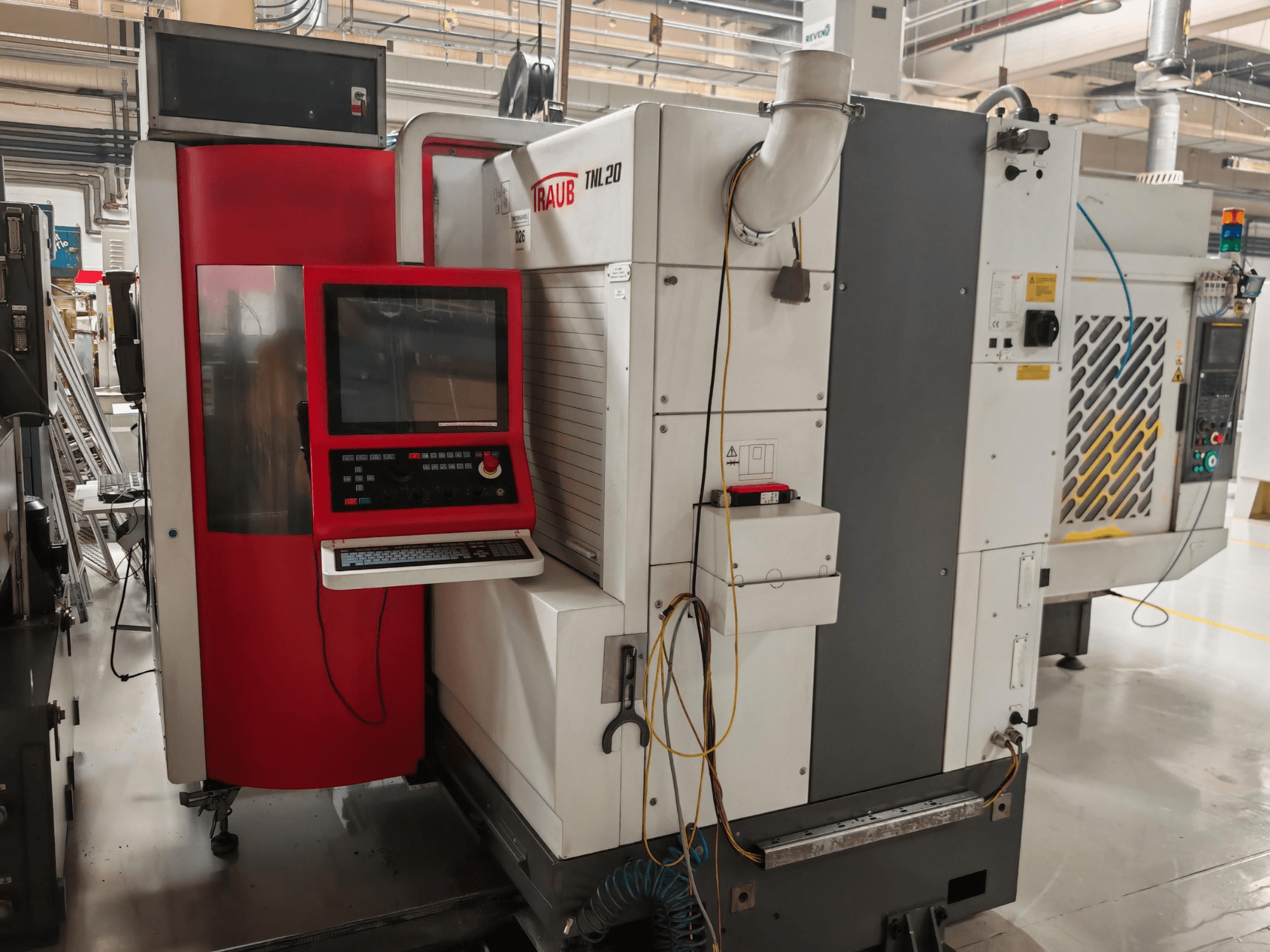 Torno de tipo suizo TRAUB TLN20, vista frontal en la que se aprecian el panel de control, la carcasa roja y los detalles industriales.