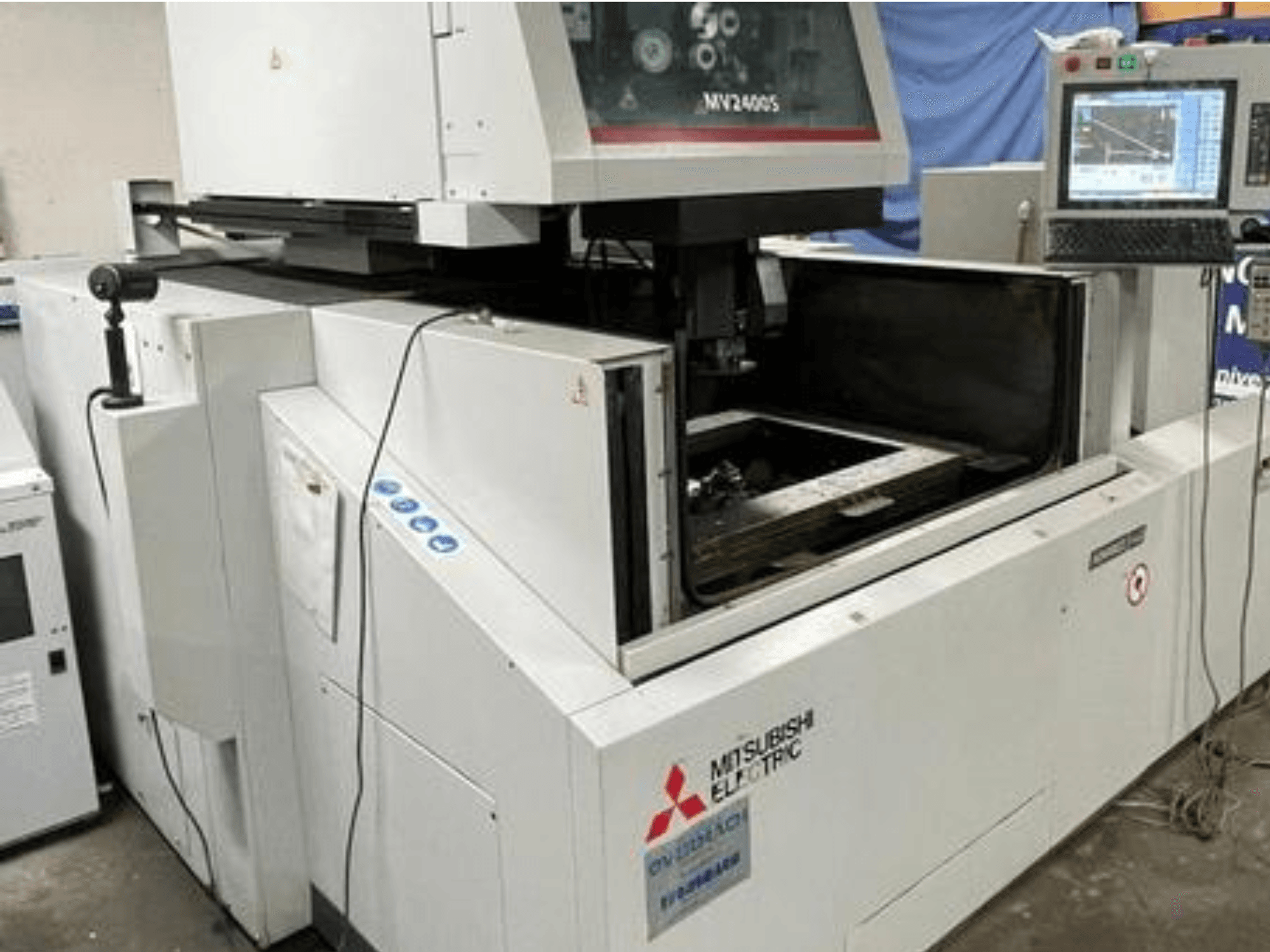 Máquina de electroerosión por corte de hilo Mitsubishi Electric MV2400S, vista frontal, mostrando el panel de control y el área de trabajo abierta.