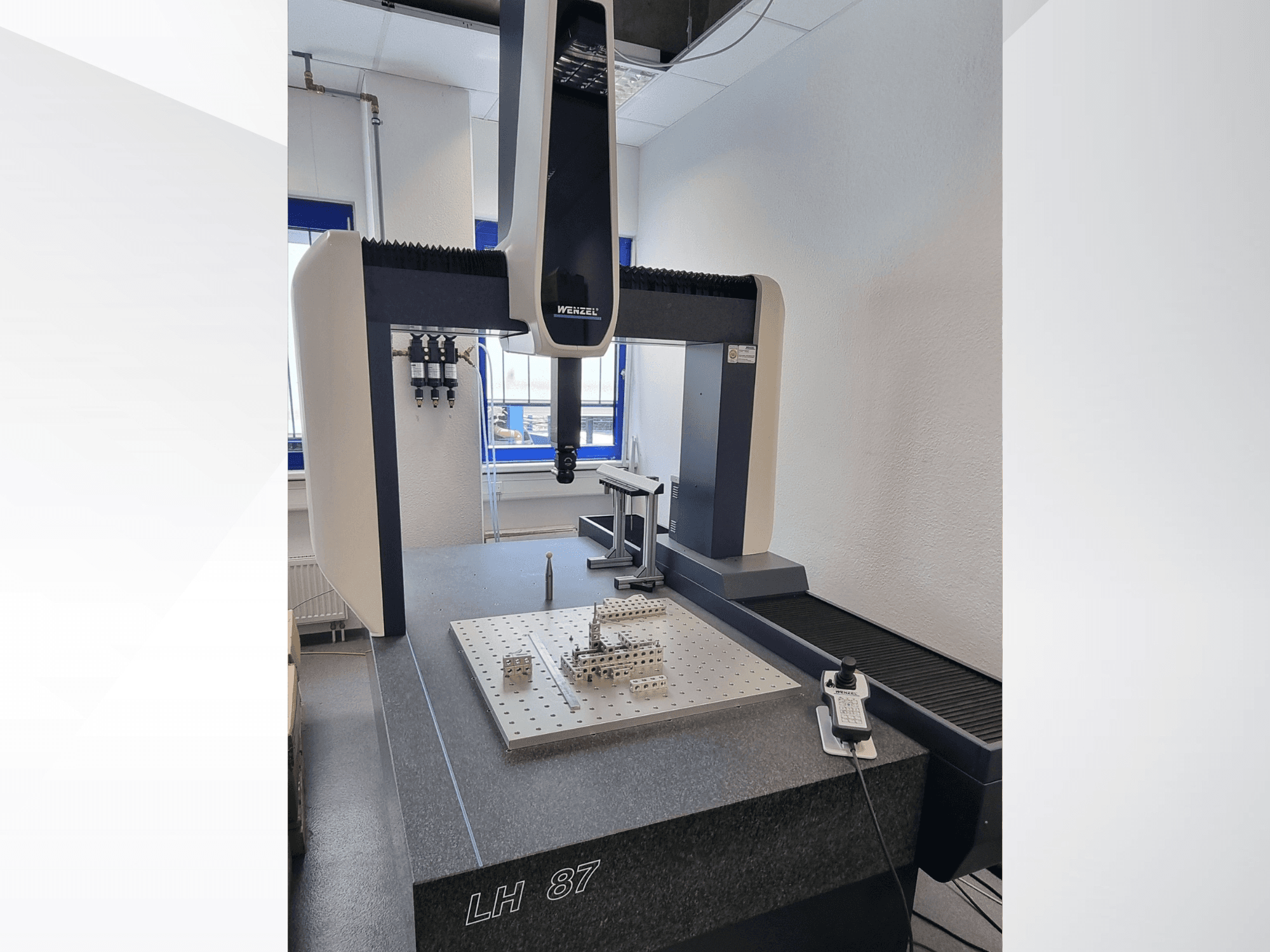 Máquina de medición por coordenadas (CMM) Wenzel LH 87 en un laboratorio, vista frontal con la sonda de medición situada sobre una placa de precisión y el controlador digital a la vista.