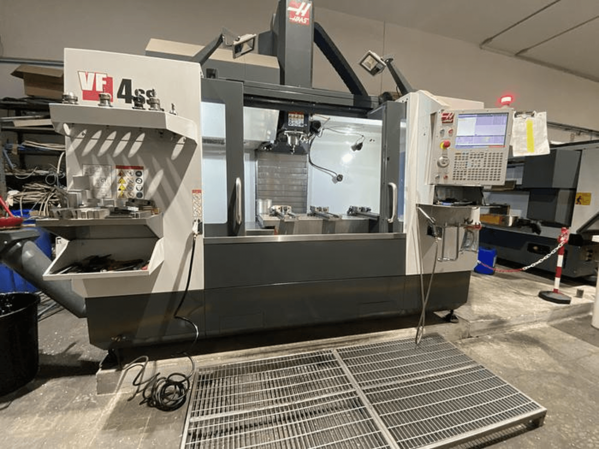 Fresadora CNC Haas VF-4SS, vista frontal, con almacenamiento de herramientas, panel de control y área de trabajo visible en un taller.