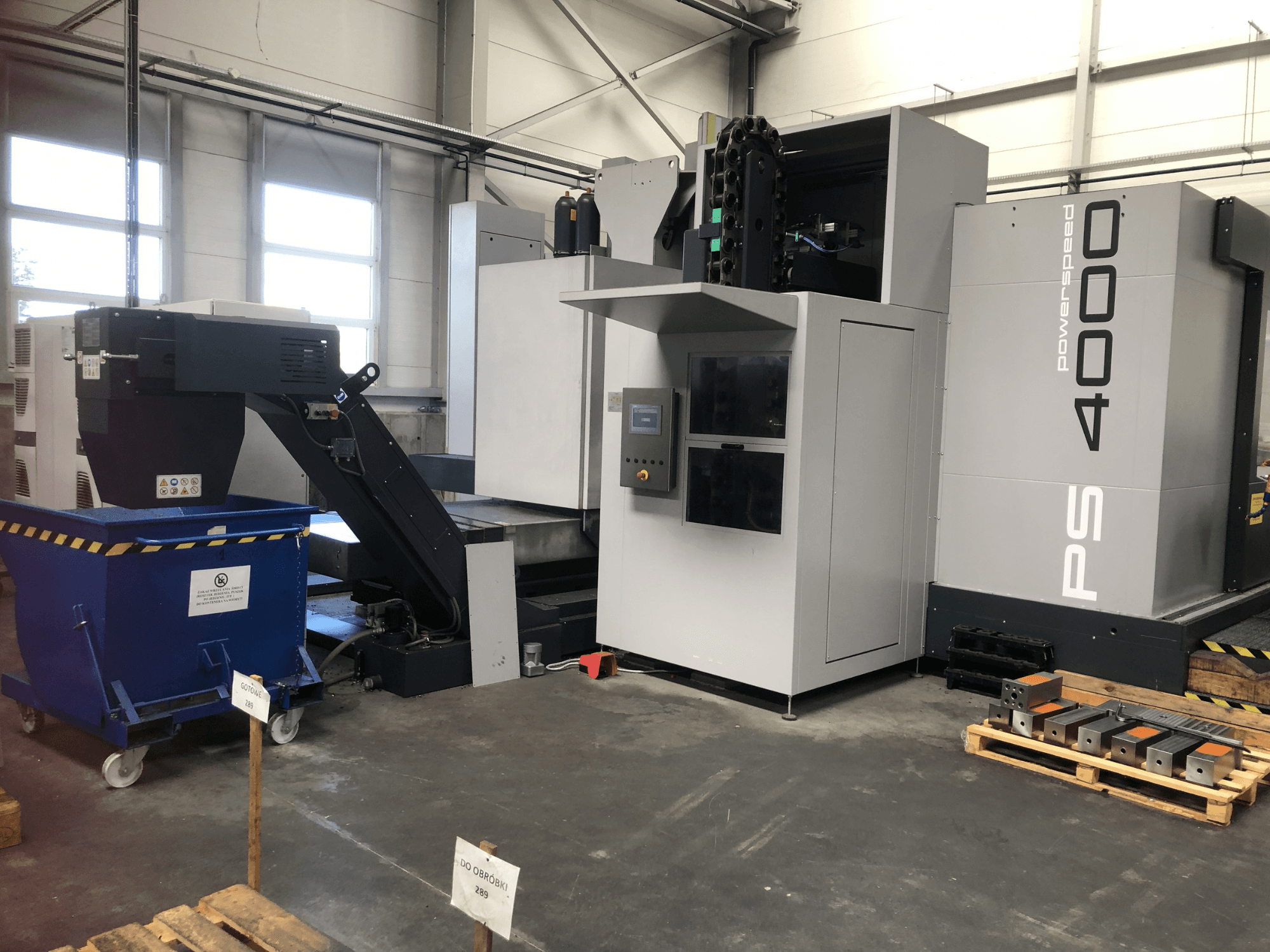 Centro de mecanizado horizontal SHW PowerSpeed 4000 en un entorno industrial, en el que se pueden apreciar el panel de control, la cinta transportadora y las piezas de trabajo.