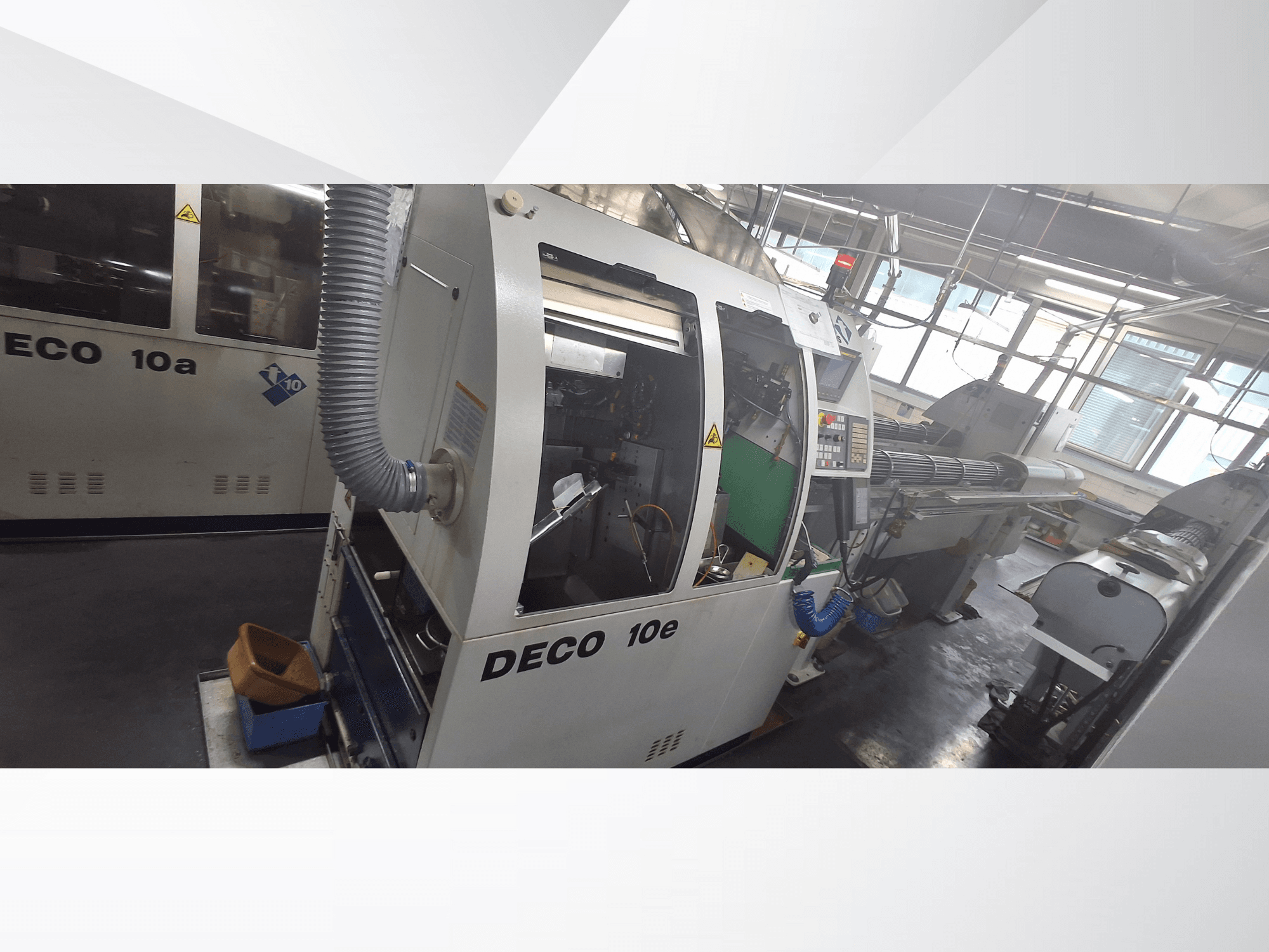 Máquina CNC DECO 10e en vista lateral, con panel de control, interior verde y manguera de escape conectada.