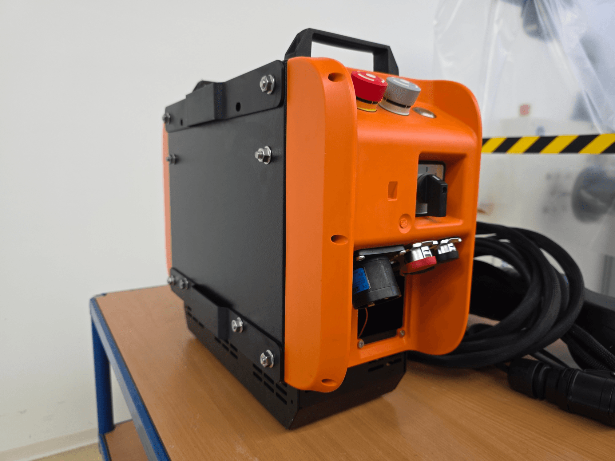 Controlador de brazo robótico KASSOW ROBOTS KR1205, vista lateral que muestra el diseño naranja y negro, los puertos de entrada/salida y los cables.