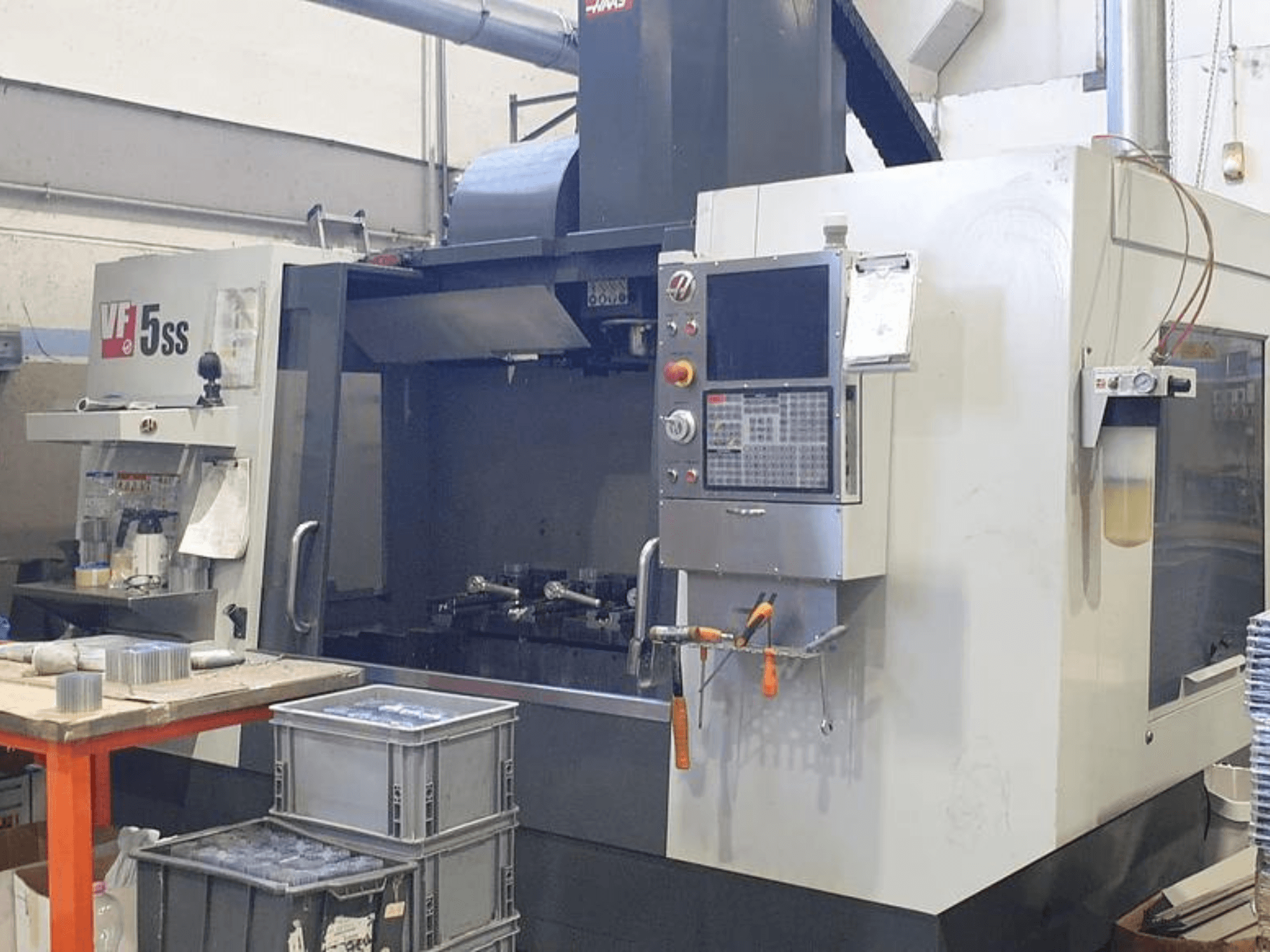 Centro de mecanizado vertical HAAS VF-5SS en vista frontal, mostrando el panel de control, el espacio de trabajo y los compartimentos de almacenamiento.