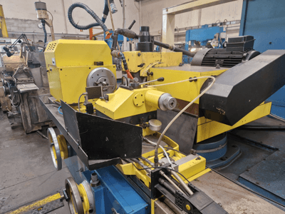 Máquina industrial amarilla con una sección negra, con un dial y mangueras, vista de frente con un ligero ángulo.