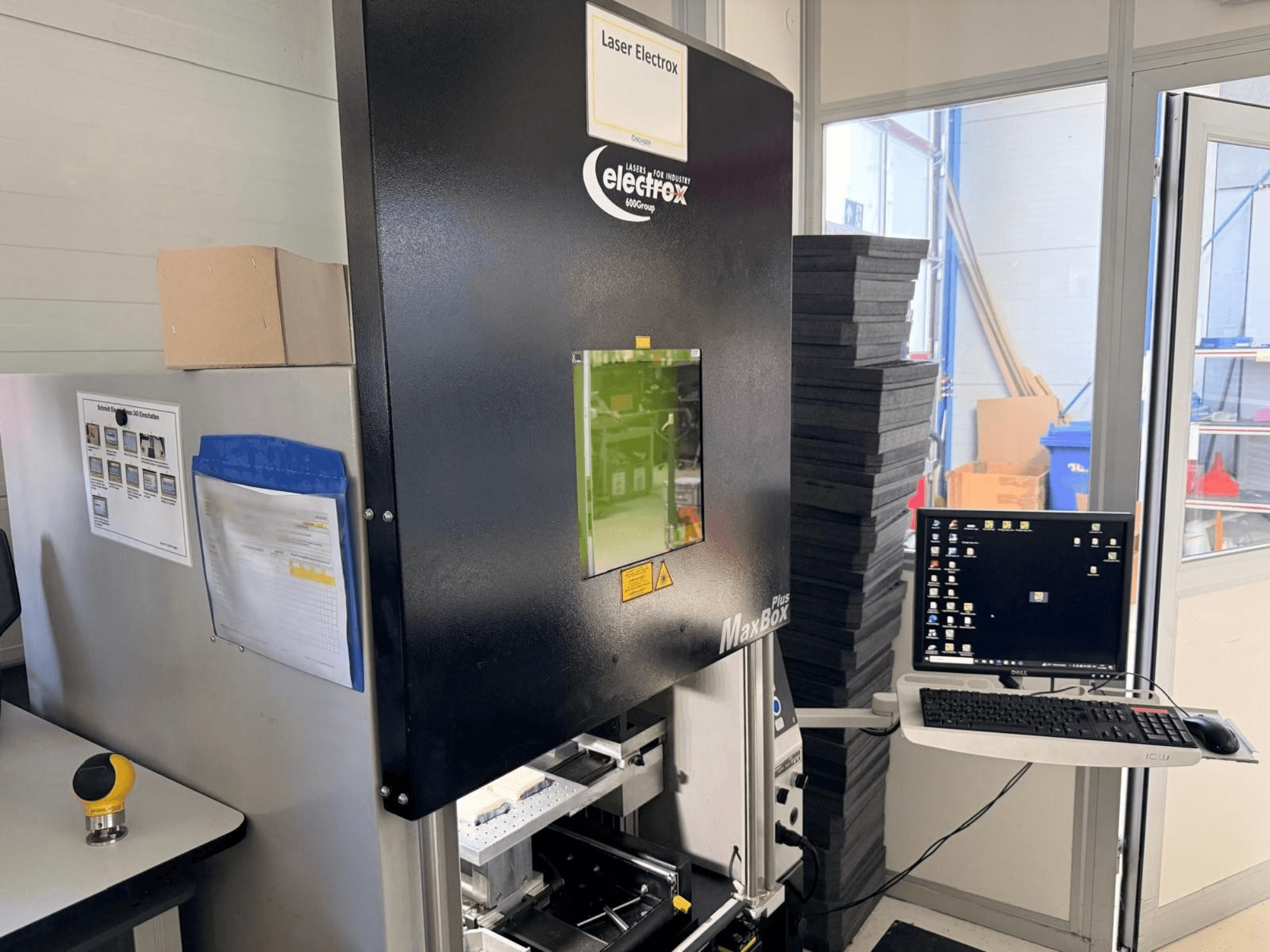 Máquina de marcado láser ELECTROX MaxBox Plus vista de perfil, con monitor de control, ventana de visualización verde y área de trabajo.