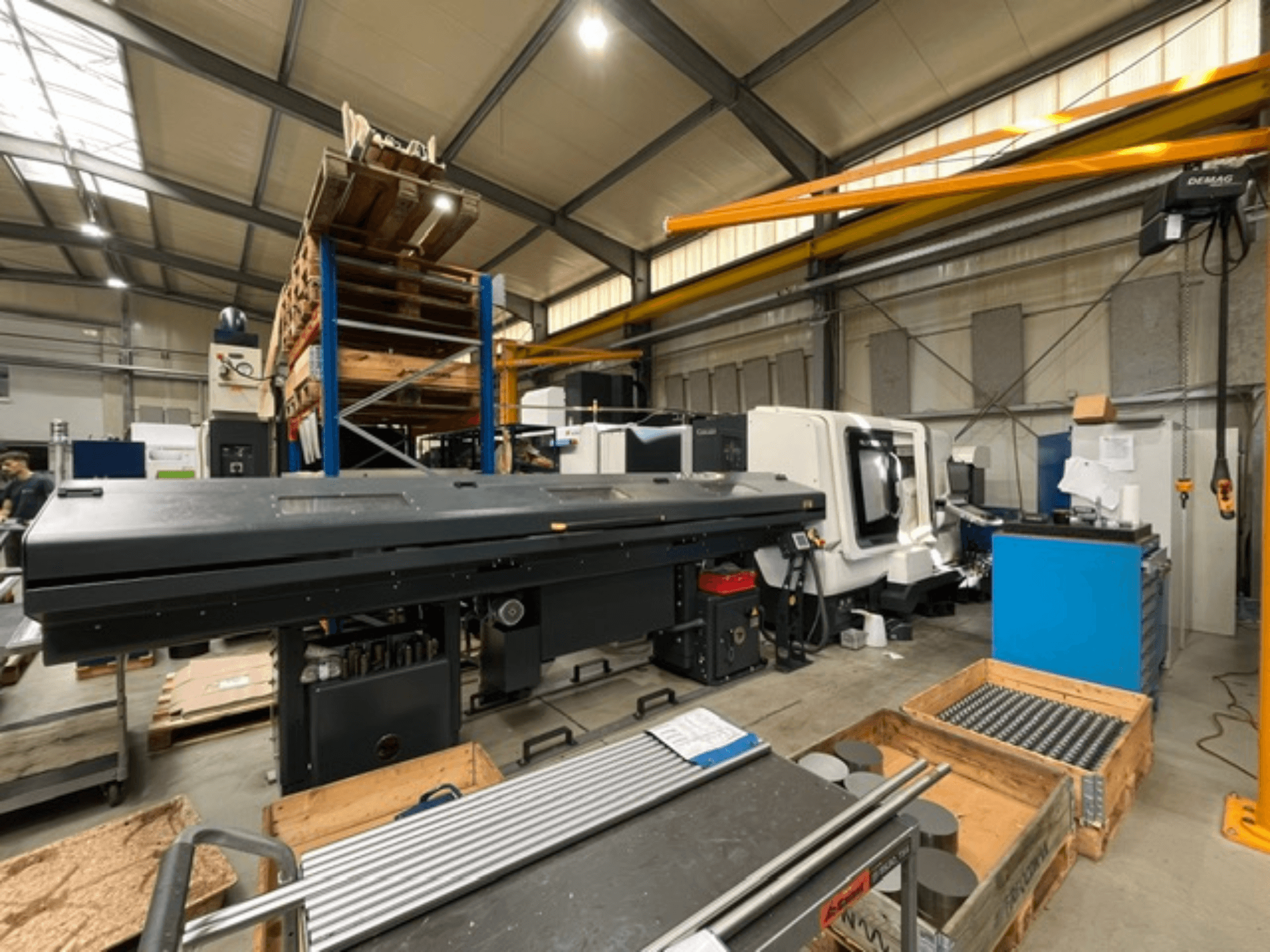 Torno horizontal DMG MORI MORI NLX 2500/700 SY en un entorno industrial, visto de perfil, con las herramientas y los palés a la vista.
