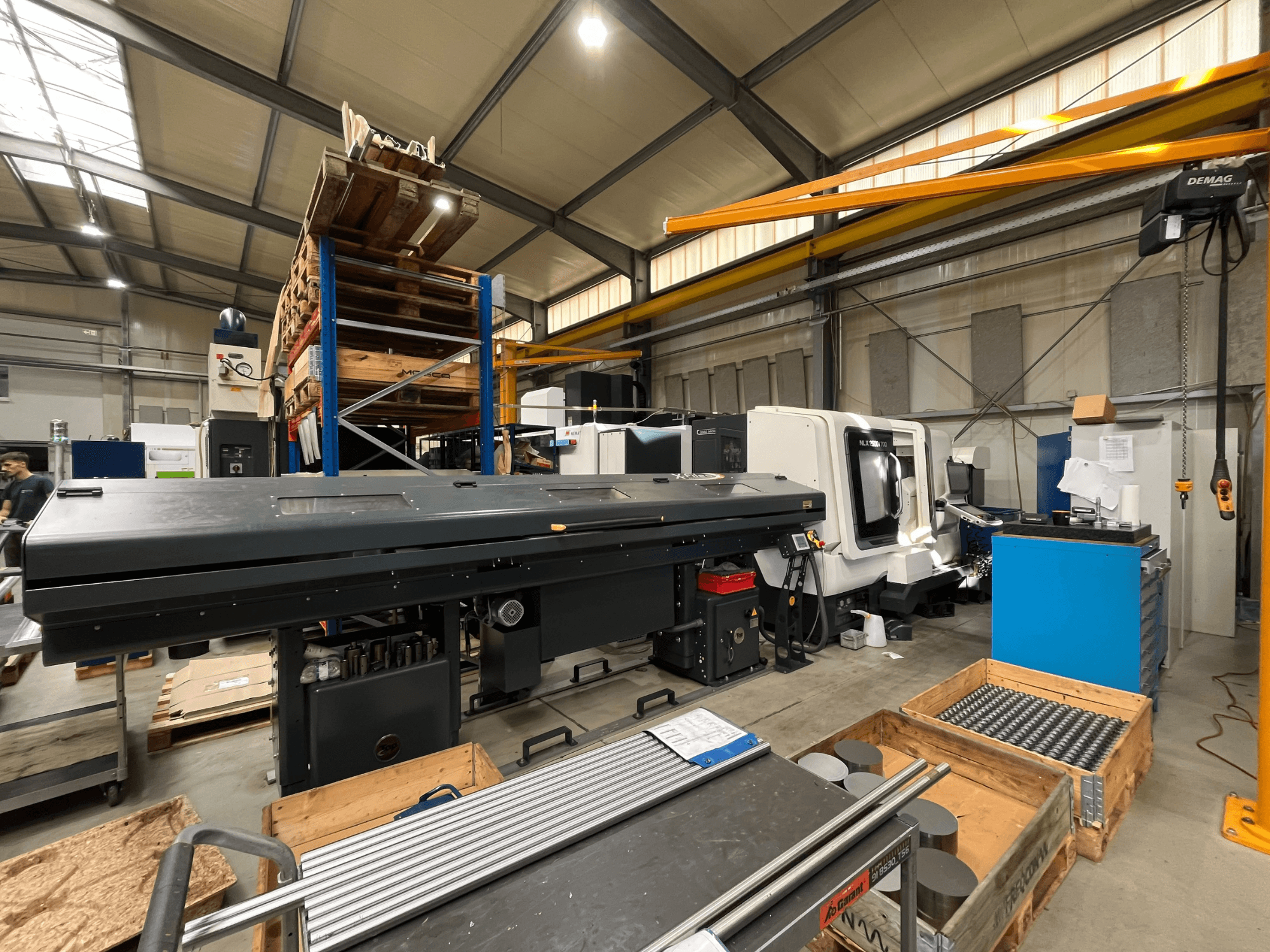 Torno horizontal DMG MORI MORI NLX 2500/700 SY en un taller, visto de perfil, con el almacén y las herramientas al fondo.