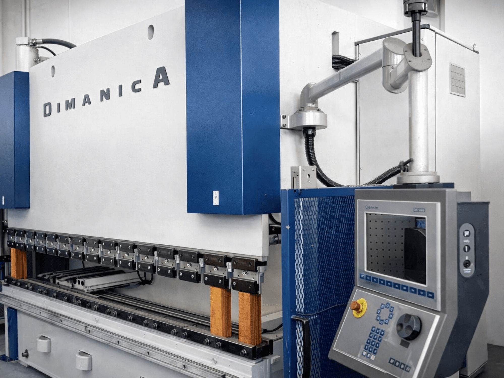 Prensa plegadora DINAMICA 3000x100 de Warcom, vista lateral que muestra el panel de control y las herramientas de plegado para la fabricación de metal.