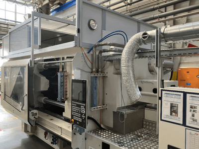 Máquina industrial de la marca X, vista lateral que muestra el panel de control, los conductos y los componentes de la maquinaria en un entorno de fábrica.