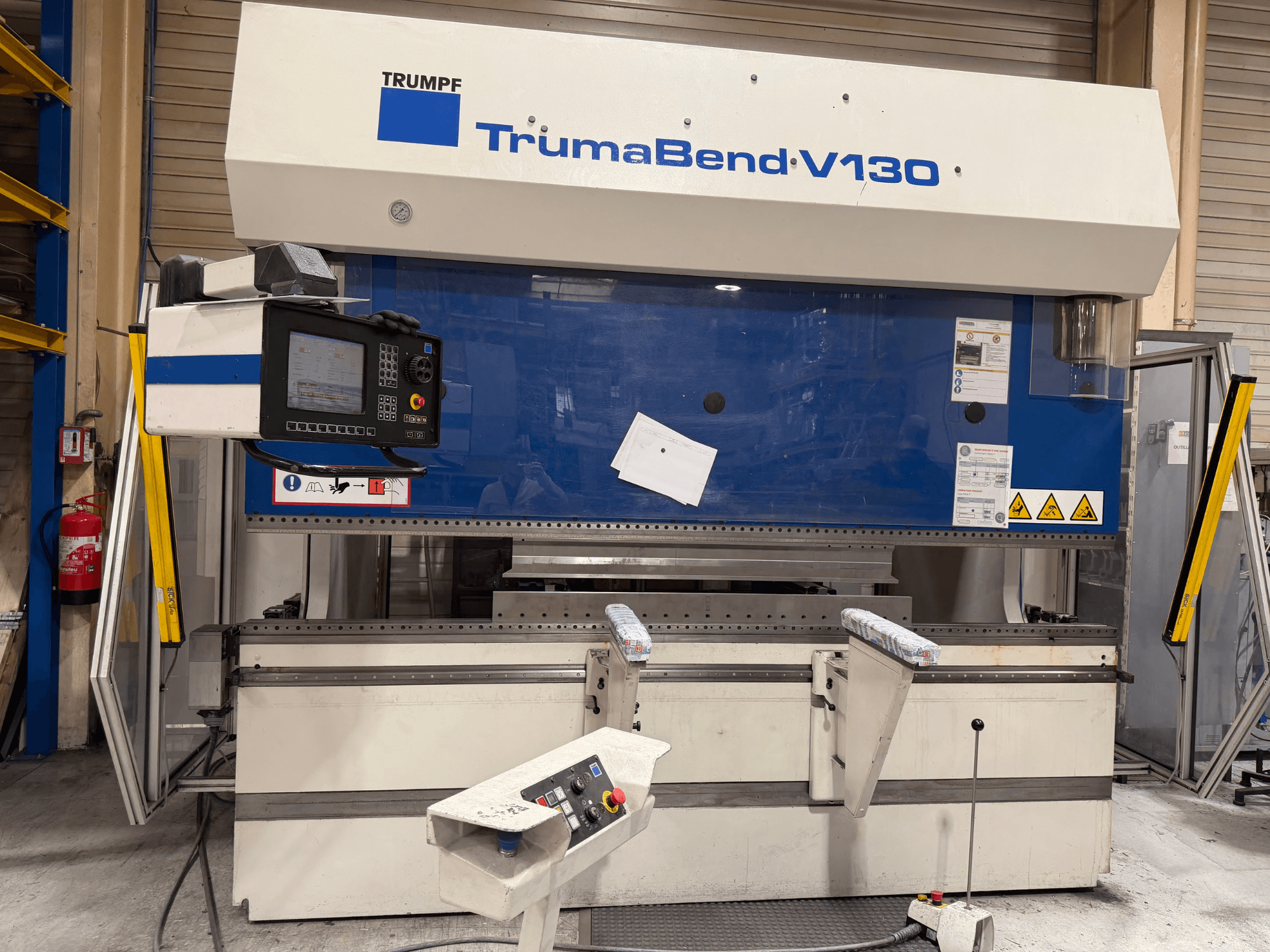 Plegadora TRUMPF TrumaBend V130 en un entorno industrial, con panel de control y dispositivos de seguridad; vista frontal.