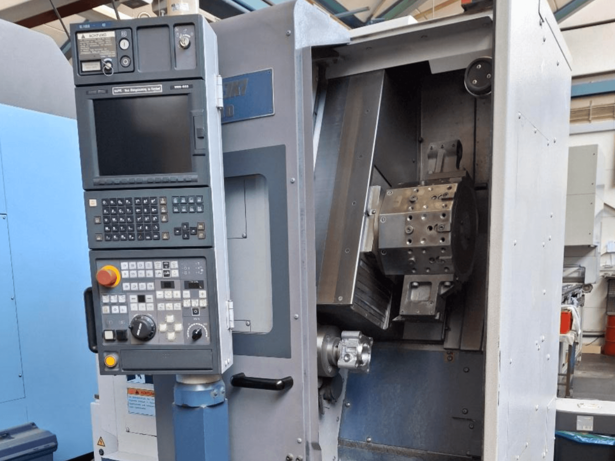Vista frontal del torno horizontal MORI SEIKI SL 1000, con panel de control y mecanismo interno detallado.