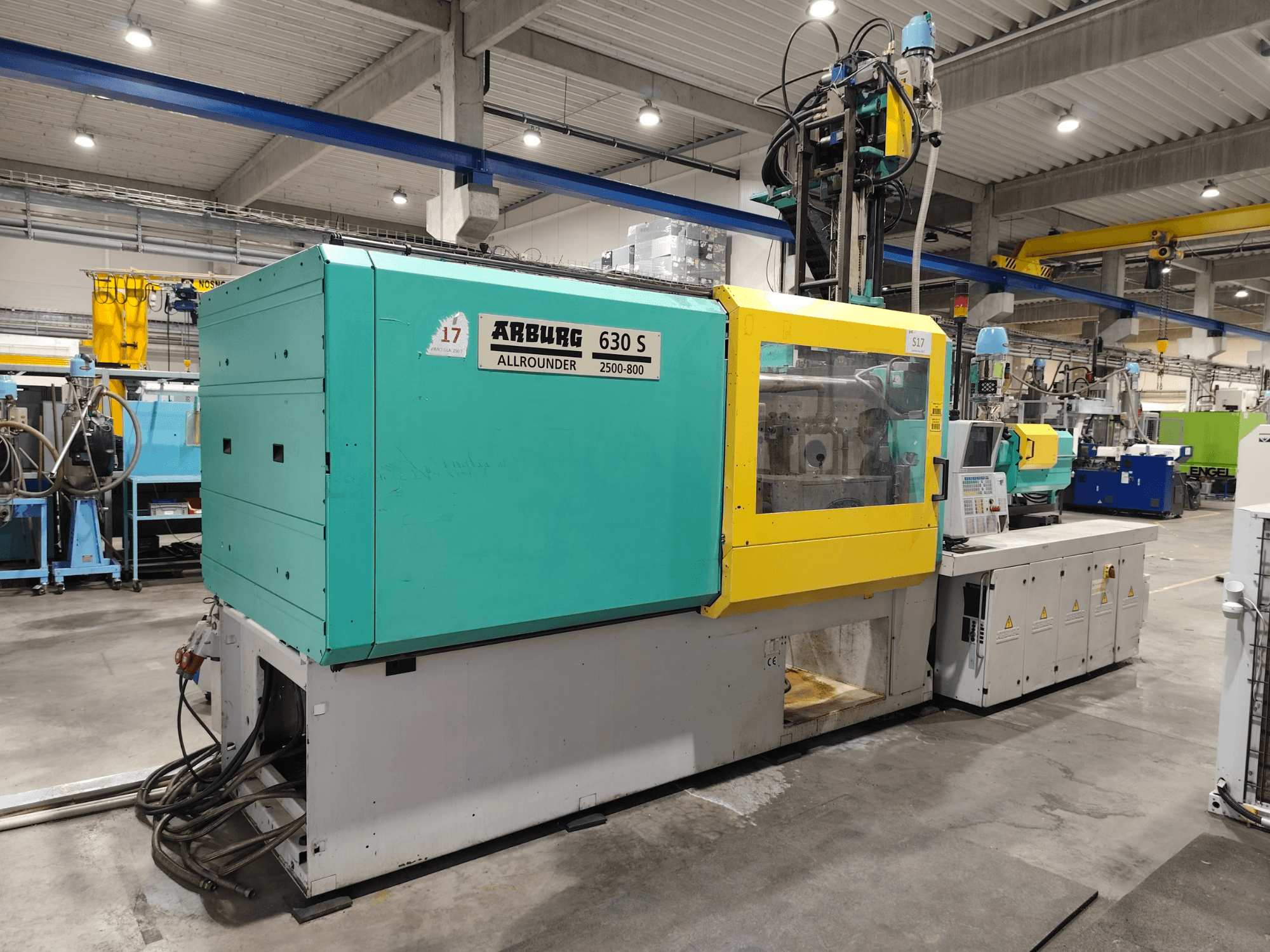 Máquina de moldeo por inyección hidráulica Arburg Allrounder 630S-2500-800/350, vista lateral, con el exterior de colores y el panel de control a la vista.