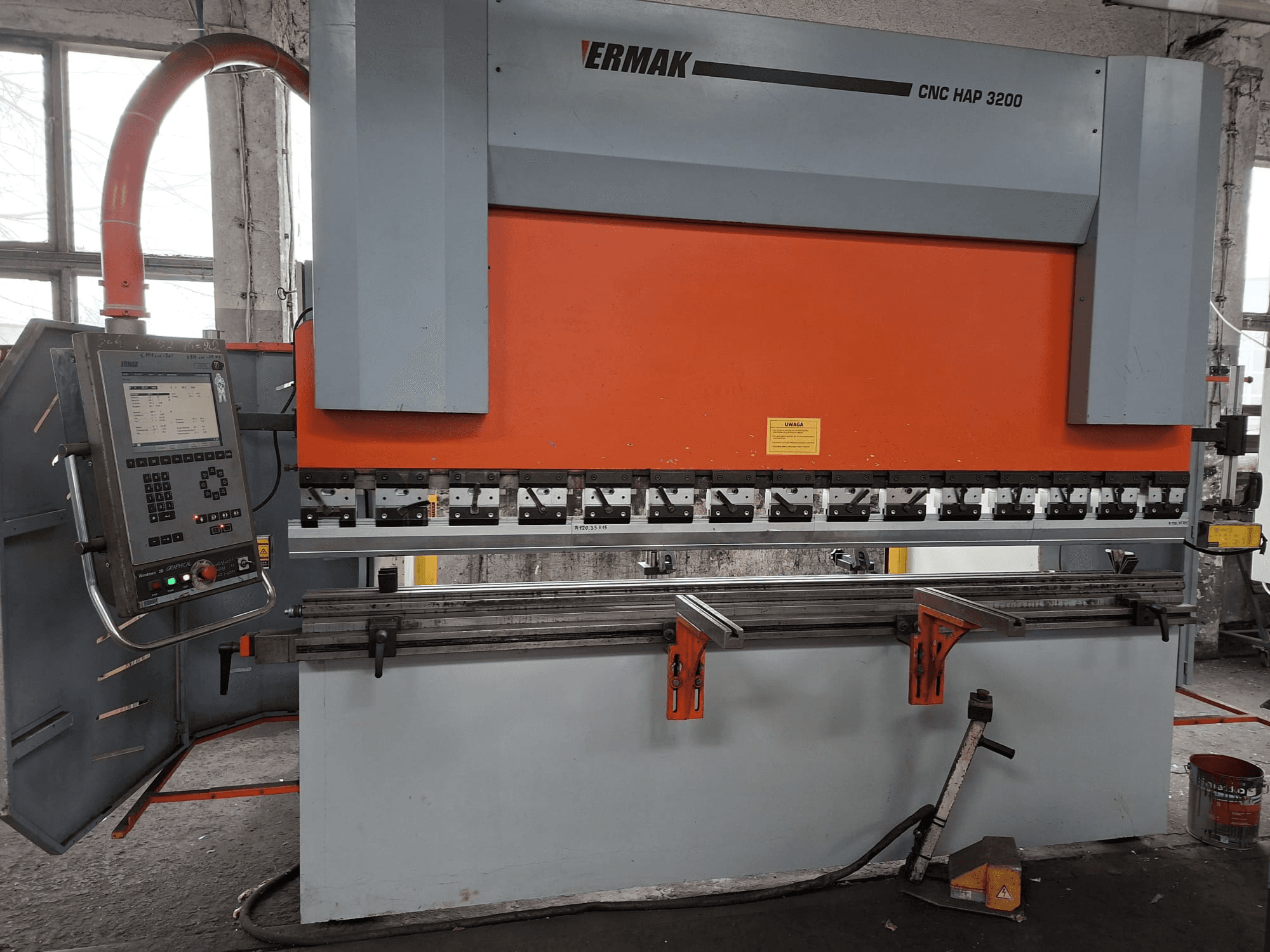 Plegadora CNC HAP 3200 de Ermak, vista frontal, con cuerpo naranja y gris, panel de control con pantalla digital y mordazas ajustables.