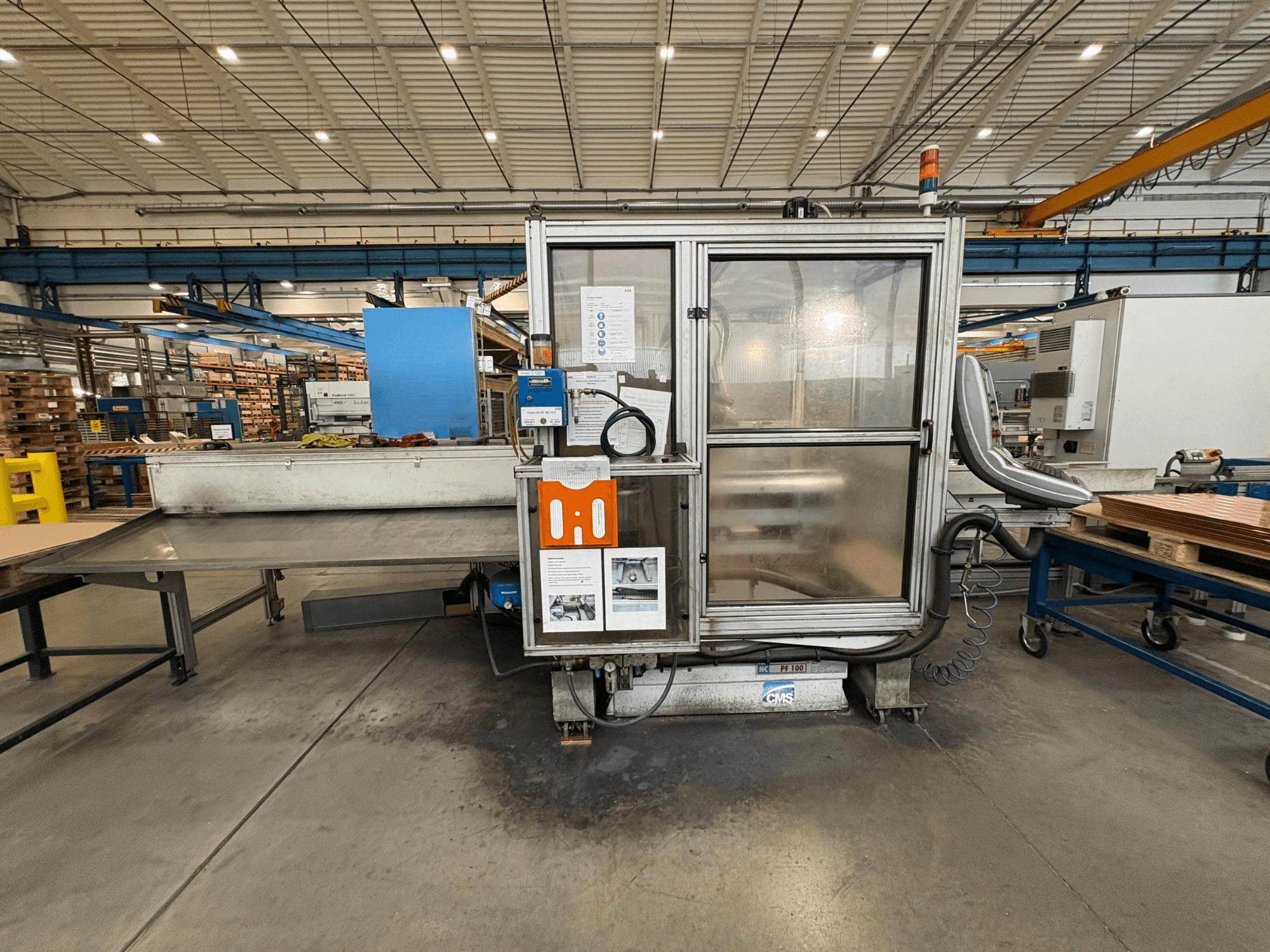 Centro de mecanizado CNC de madera CMS NC PF 100, vista frontal; incluye panel de control, armario de seguridad y mesa de trabajo.