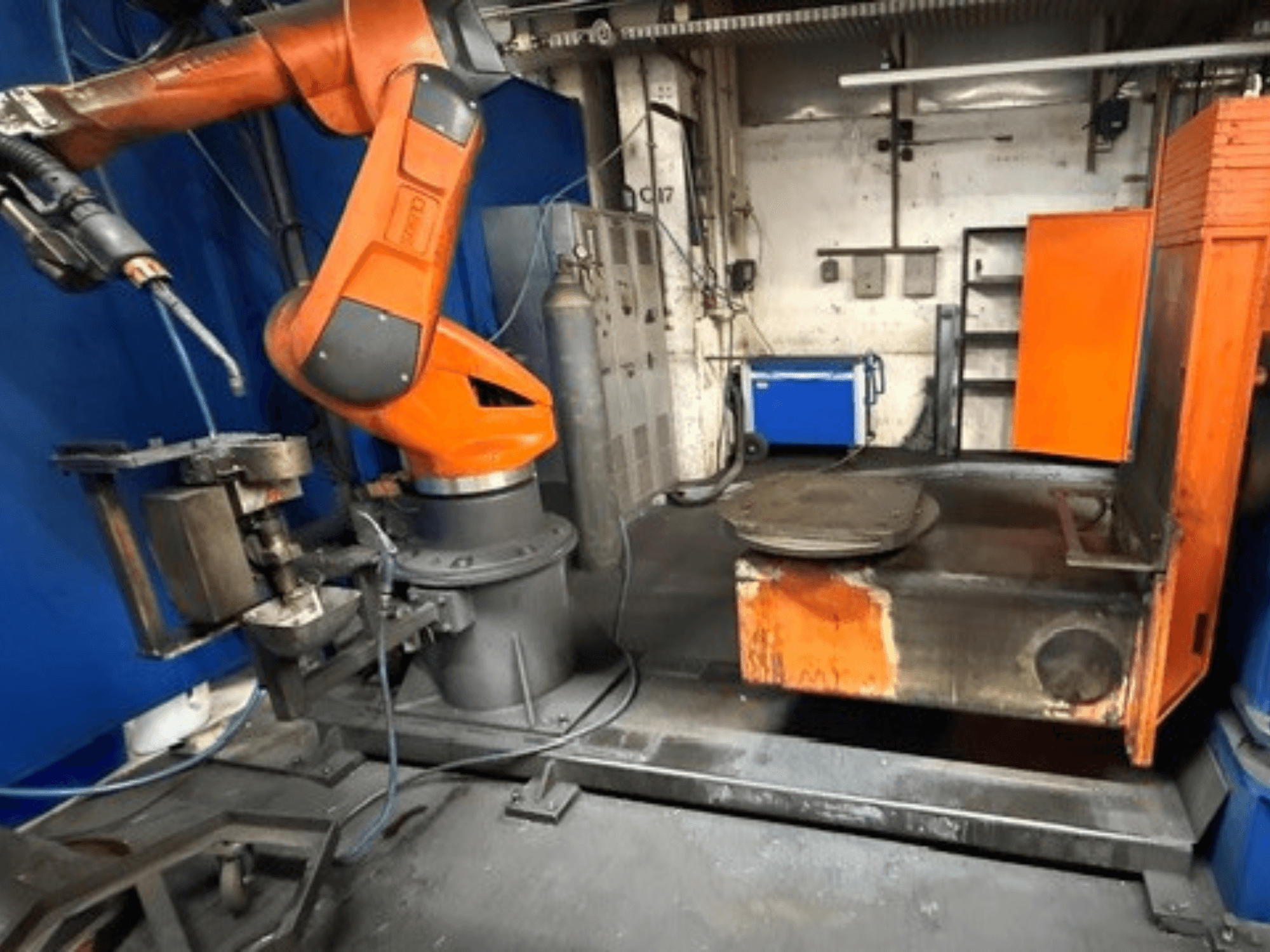 Robot de soldadura CLOOS C50 visto de frente, con un brazo robótico de color naranja y una mesa de trabajo metálica.