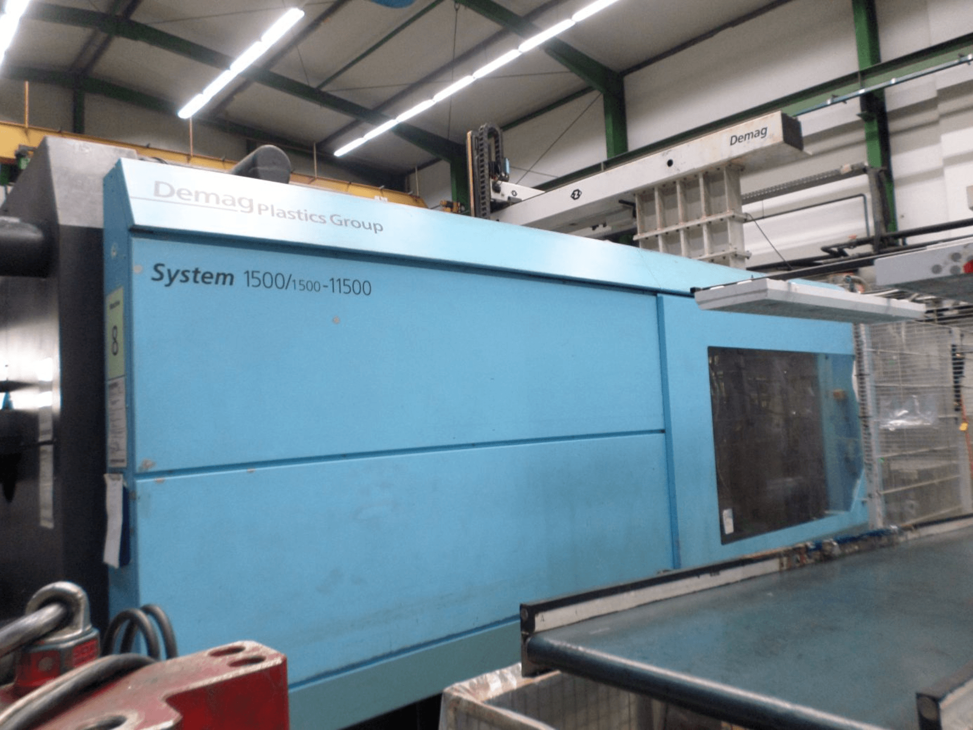 Máquina de moldeo por inyección hidráulica Demag D 650 en color azul; vista lateral en la que se aprecia la etiqueta «System 1500/1500-11500» y la zona de mando.