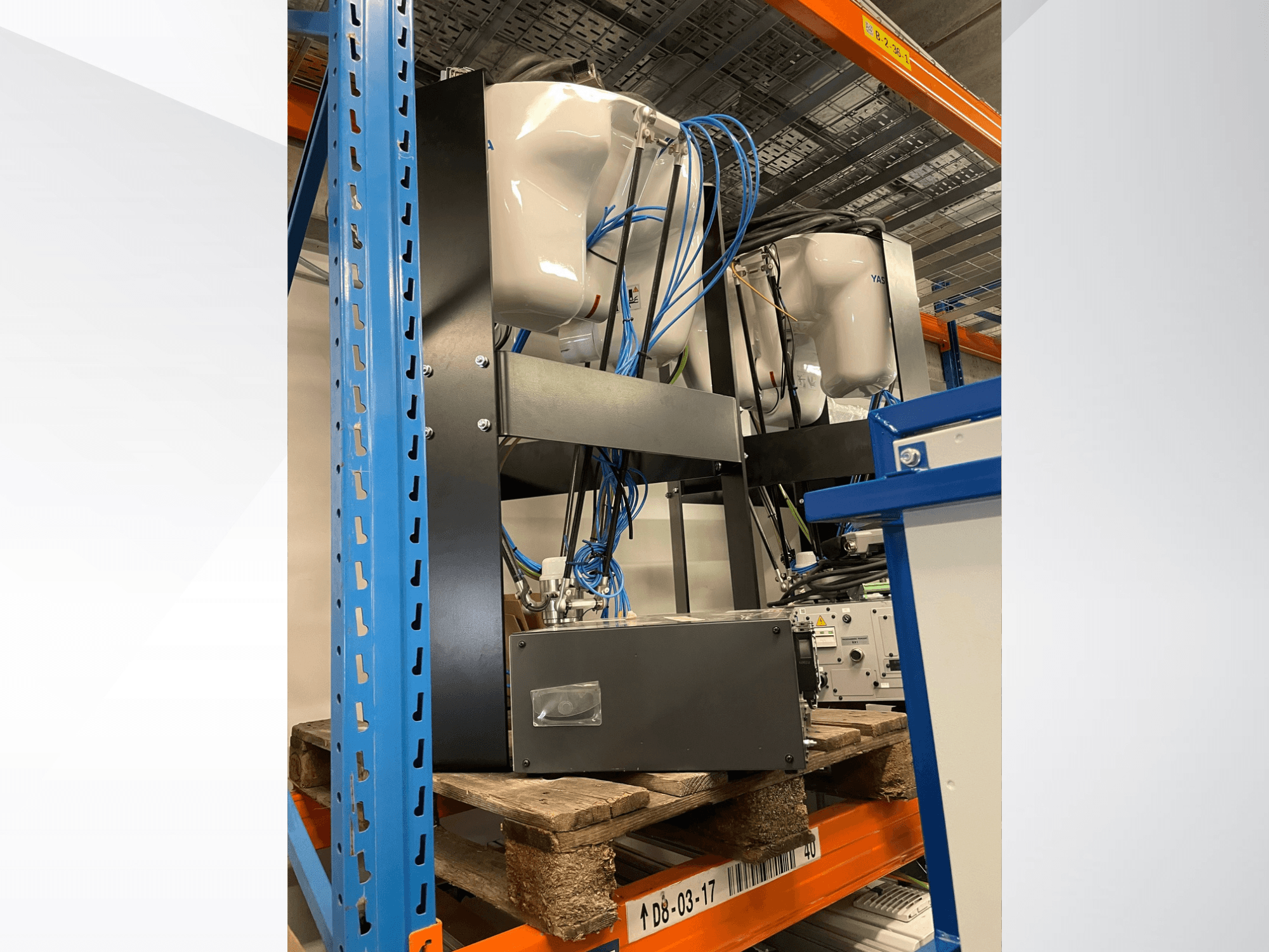 Brazo robótico Yaskawa Motoman MPP3H, visto de perfil, con el cableado y los componentes visibles sobre una estantería.
