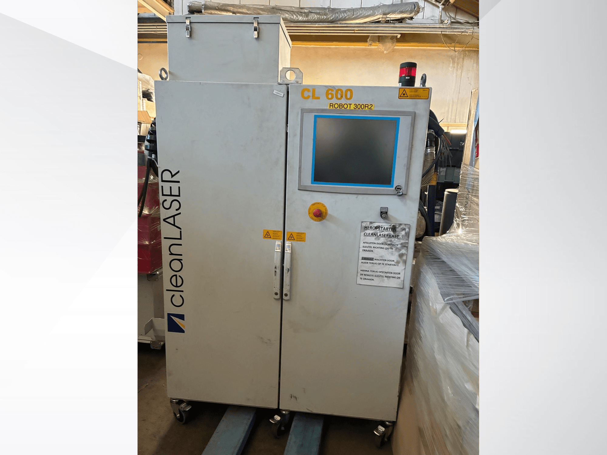 Sistema de automatización CLEAN LASER CL 600 visto de frente, con pantalla LCD, etiquetas de advertencia y botones de control en la puerta.