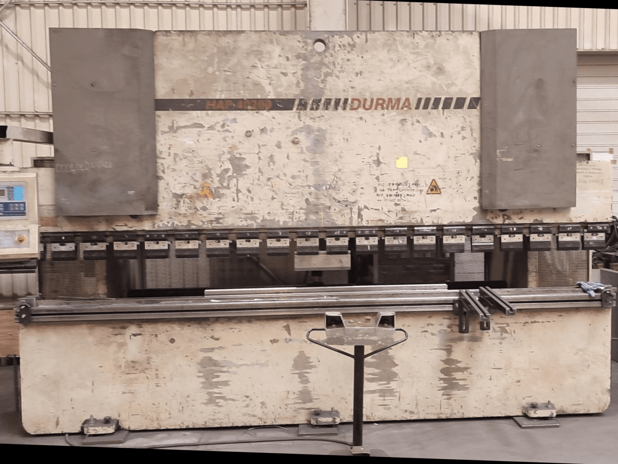 Vista frontal de la plegadora Durma HAP 40200, con el exterior desgastado, el panel de control y las herramientas de sujeción visibles en la superficie de trabajo.