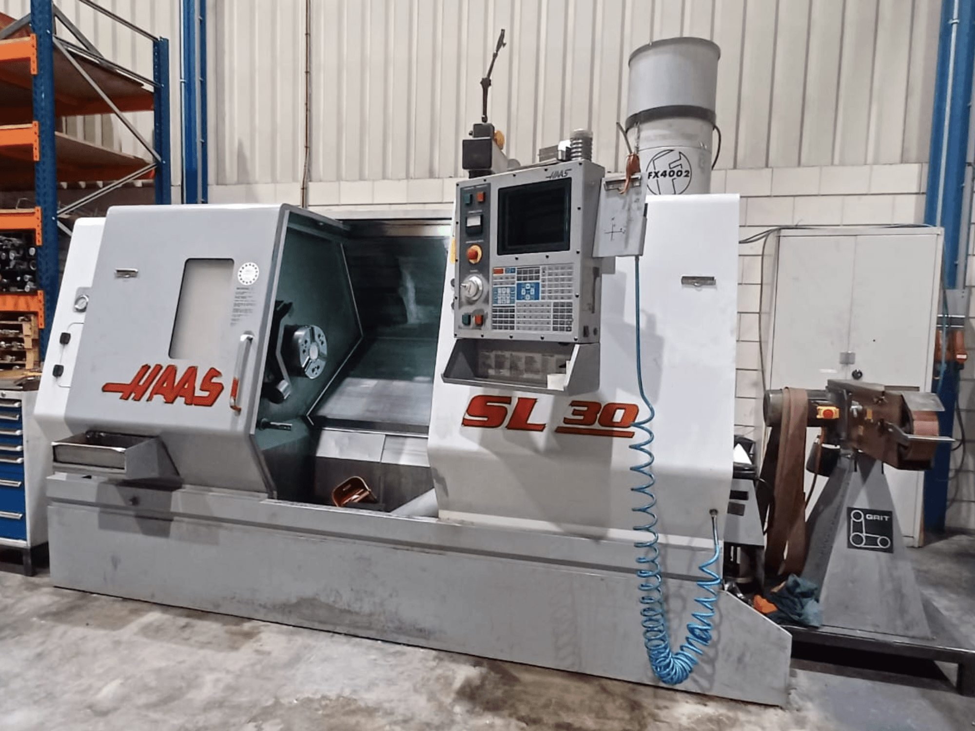 Torno CNC Haas SL 30 en vista lateral, mostrando el panel de control, la zona de mecanizado y el sistema de refrigerante integrado para metalistería.